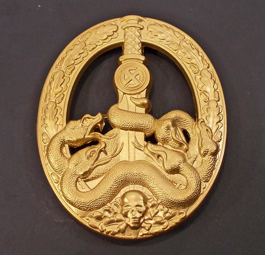 GERMAN NAZI ARMY GOLD ANTI PARTISAN BADGE: Front shows 4 snakes wrapped around a sword blade. There is a skull at the base. Surrounded by an oval oak leaf wreath. Wide vertical pinback that is maker marked 1 for the manufacturing firm of Desch