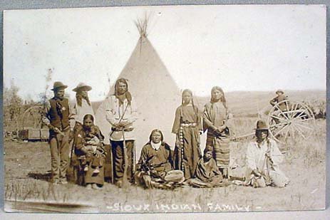 1908 RPPC REAL PHOTO POSTCARD SIOUX INDIAN FAMILY : Great image of Sioux Indian Family, poss. from Rosebud Reservation. One indian is holding a rifle and another one has a badge on his vest and is holding a pistol. Postmarked 1908 from Delmont, SD.