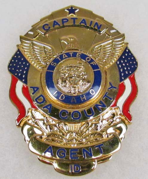 ADA COUNTY IDAHO CAPTAIN AGENT POLICE LAW BADGE: Maker marked Smith & Warren USA. This is a shield shaped badge. Two piece brass and enamel construction. Pin back