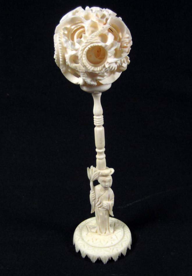 INTRICATELY CARVED IVORY BALL W/ STAND: The ball is approx. 2" diameter and has several carved balls inside. Stand is approx. 5" tall