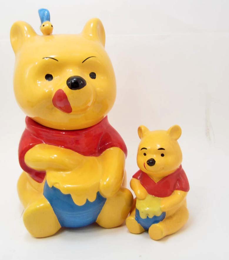 COOKIE JAR AND MATCHING BANK - WINNIE THE POOH - WALT: A fantastic matching set of Walt Disney's character Winnie the Pooh cookie jar and a small bank. The cookie jar is unmarked and measures approximately 12" tall. The bank is marked "Walt Disney Product