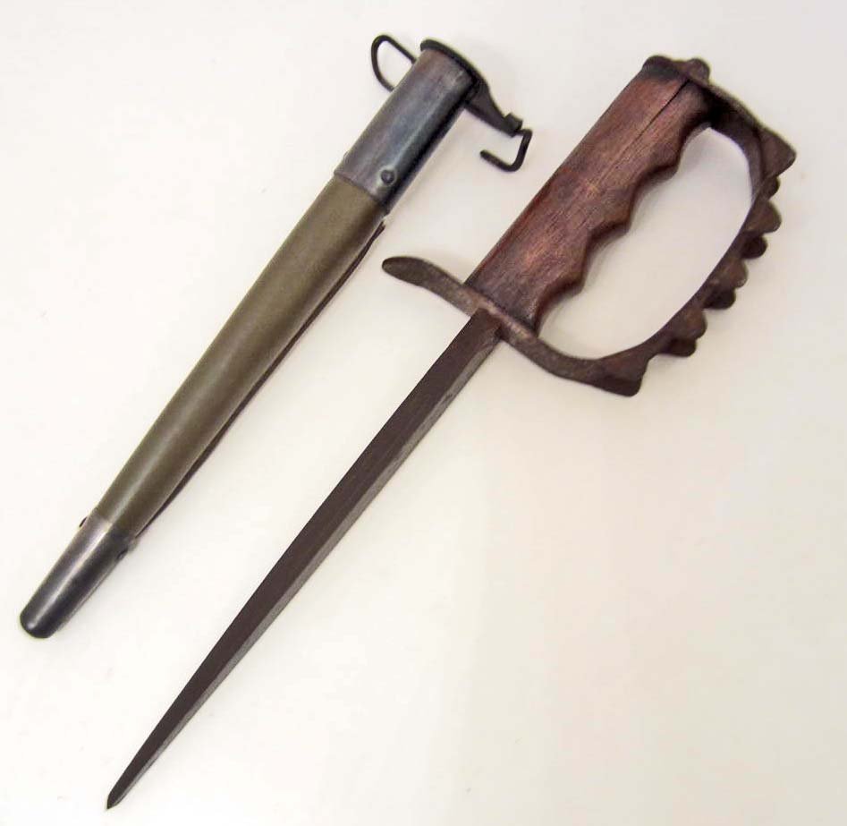 US ARMY COMBAT TRENCH KNUCKLE KNIFE W/ SCABBARD: Measures 15 ¼" long overall. The triangular steel blade measures ½" wide by 8 ¼" long. Has an oak wood handle. The steel knuckle D guard is maker marked A C O USA 1917. Includes the OD green leathe