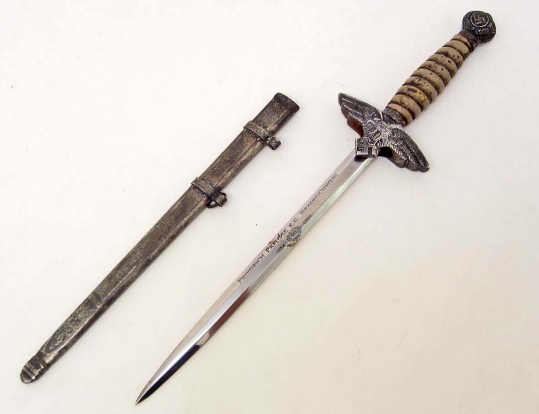 GERMAN NAZI MINIATURE LUFTWAFFE 2ND MODEL OFFICERS: W/ SCABBARD. Approx. 9 5/8" long overall. Has an engraved steel blade that reads Friedrich K G Braunschweig 1884 50 1934. The blade is approx. 7/16" by 6". Has a wire wrapped wood handle. The scabbard