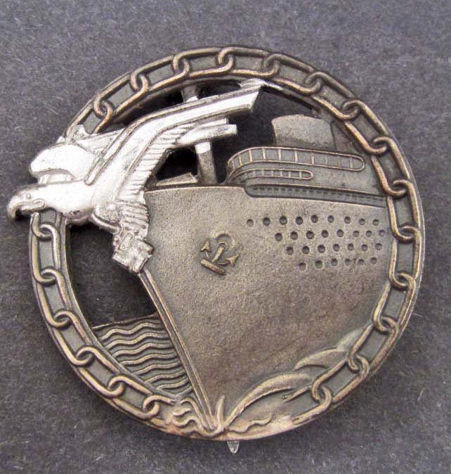 GERMAN NAZI NAVAL BLOCKADE RUNNER BADGE: Has a wide vertical pin back. Maker marked Fec Otto Placzek Berlin Ausf Schwerin Berlin. Nickel construction