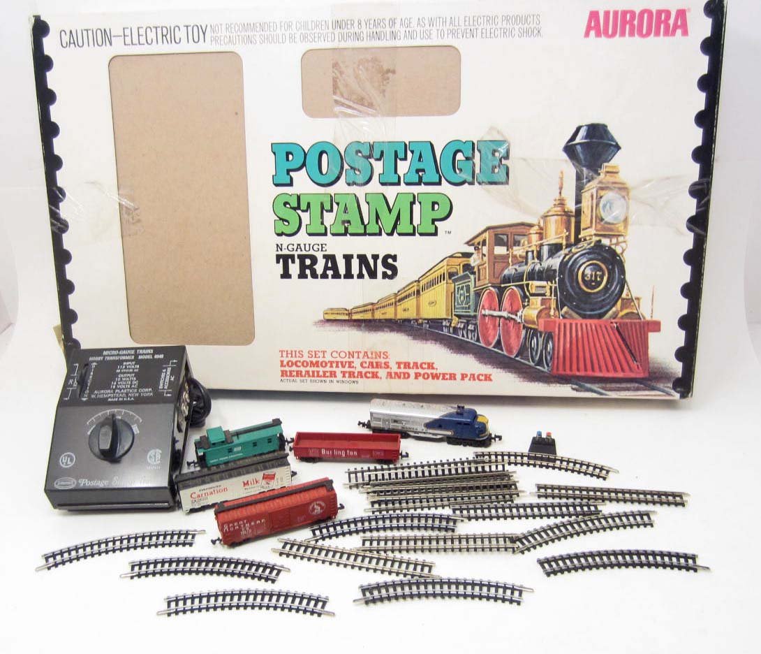 1973 AURORA POSTAGE STAMP TRAIN SET IN ORIG. BOX: N-Gauge Train set. Great condition. Box is a little rough. Contains 5 train cars including the engine, power pack, track and rerailer track and instruction manual.