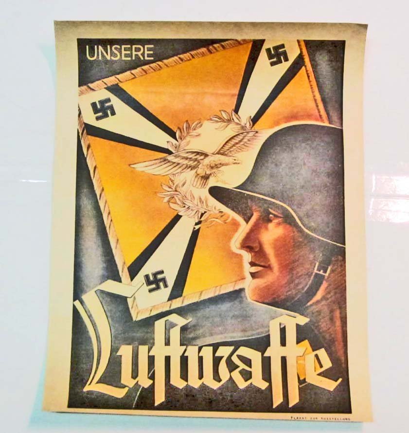 GERMAN NAZI LUFTWAFFE SOLDIER RECRUITING POSTER: Measures 11 3/4" wide by 15 3/8" tall. The front shows a Luftwaffe soldier wearing a combat helmet. He is beside a Luftwaffe Regimental Flight Standarte Flag. It reads Unsere Luftwaffe. The bottom rig