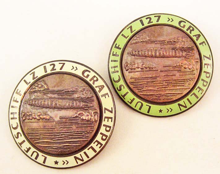 LOT OF 2 GERMAN NAZI LZ 127 GRAF ZEPPELIN AIR SHIP: They measure 1 3/4" in diameter. The front reads Luftschiff LZ 127 Graf Zeppelin. The reverse side is maker marked FLL. Both have a thin horizontal pin back. Two piece copper construction with enamel.
