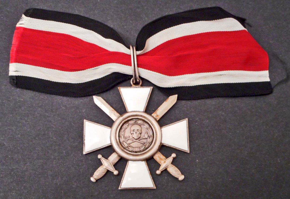 GERMAN NAZI WAFFEN SS SHULTZ STAFFEL SKULL NECK ORDER: Measures 2" wide by 2" tall. There is a skull and cross bones in the center. There is a suspension loop at the top. This is a four armed maltese cross with swords for a combatant. Includes the present