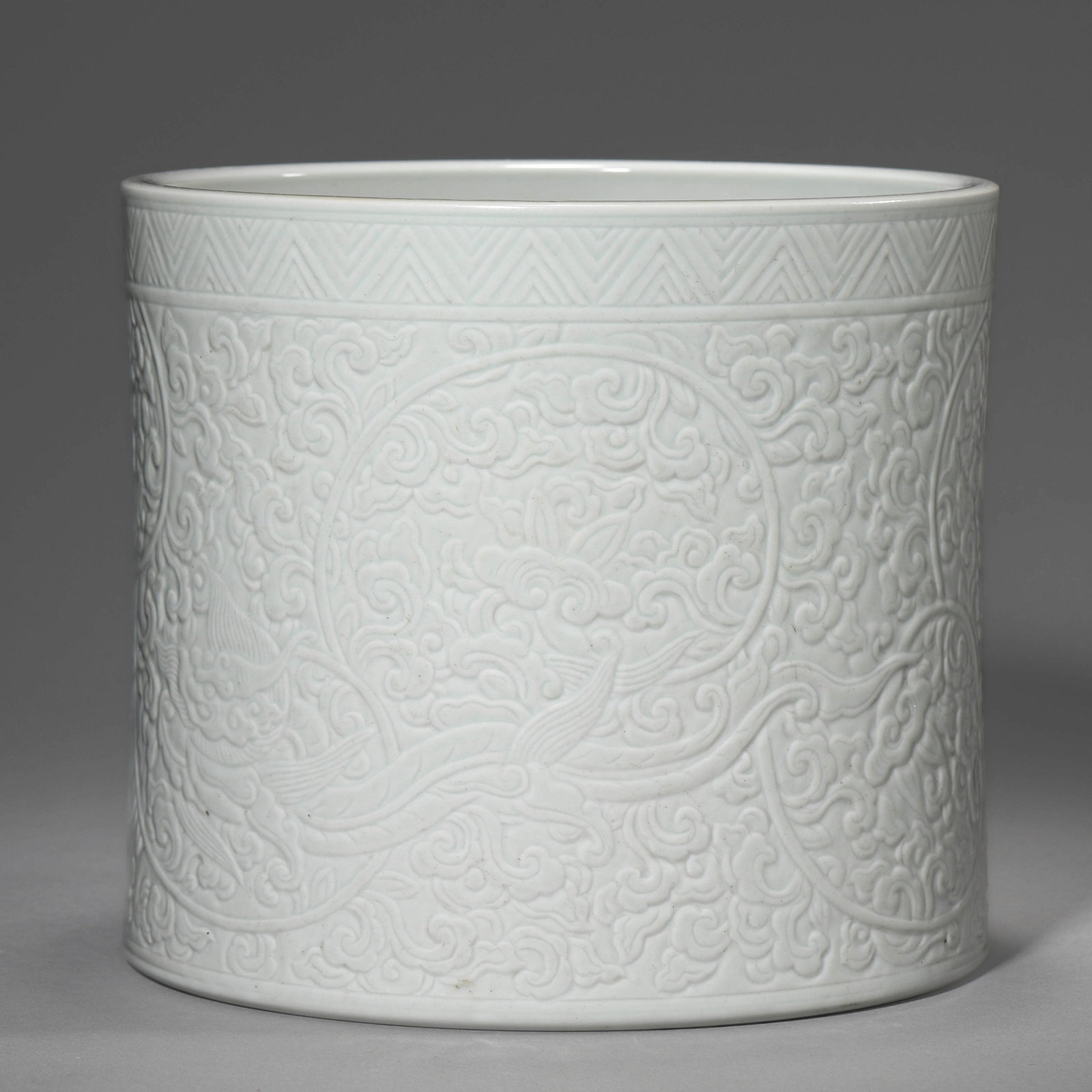 A WHITE-GLAZED 'FLOWERS' BRUSH POT: A WHITE-GLAZED 'FLOWERS' BRUSH POT Height: 6 11/16 in. (17 cm), Diameter: 7 11/16 in. (19.5 cm)
