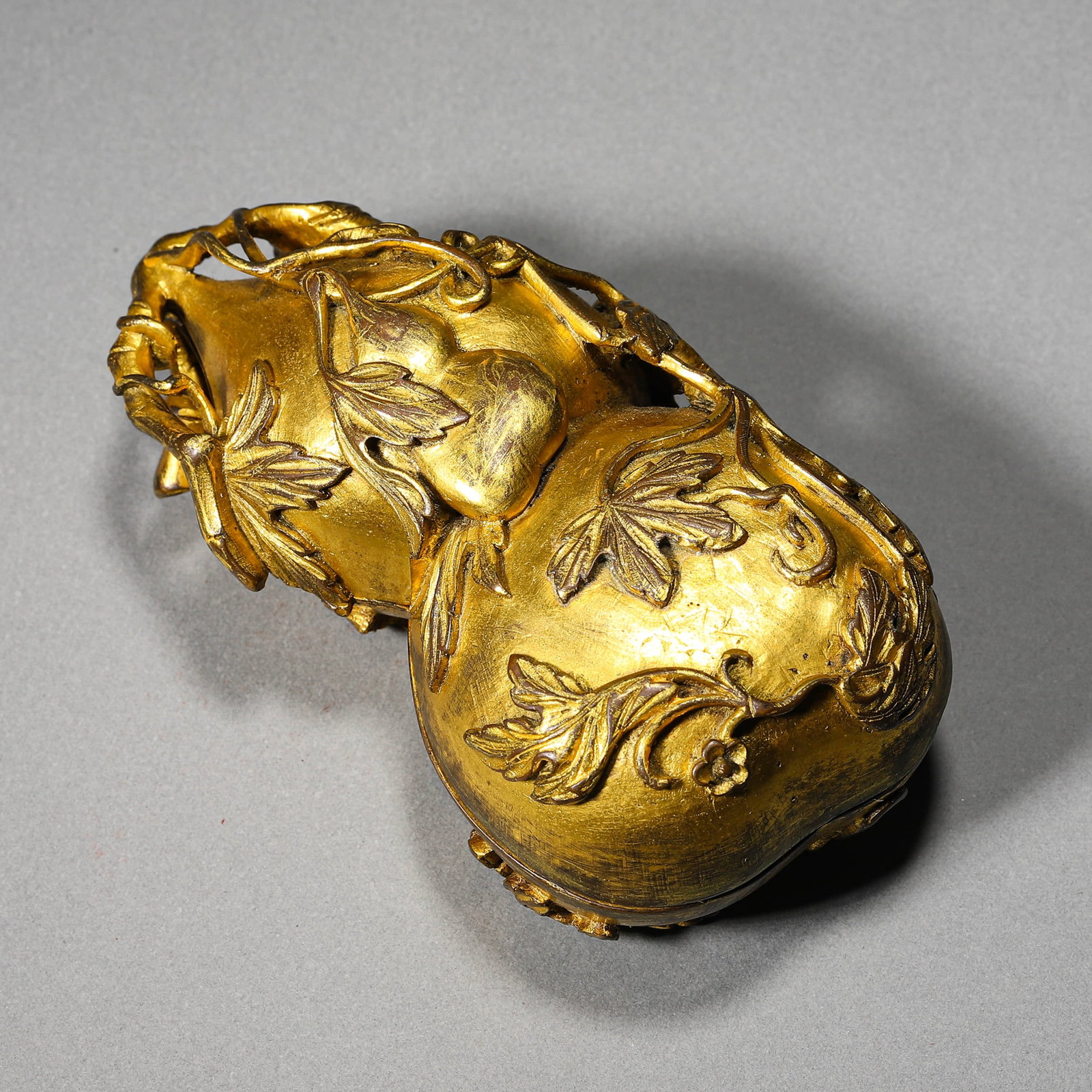 A GILT-BRONZE GOURD SHAPED COVERED BOX: A GILT-BRONZE GOURD SHAPED COVERED BOX Length: 4 1/2 in. (11.5 cm), Width: 2 5/16 in. (5.8 cm), Height: 1 9/16 in. (4 cm)