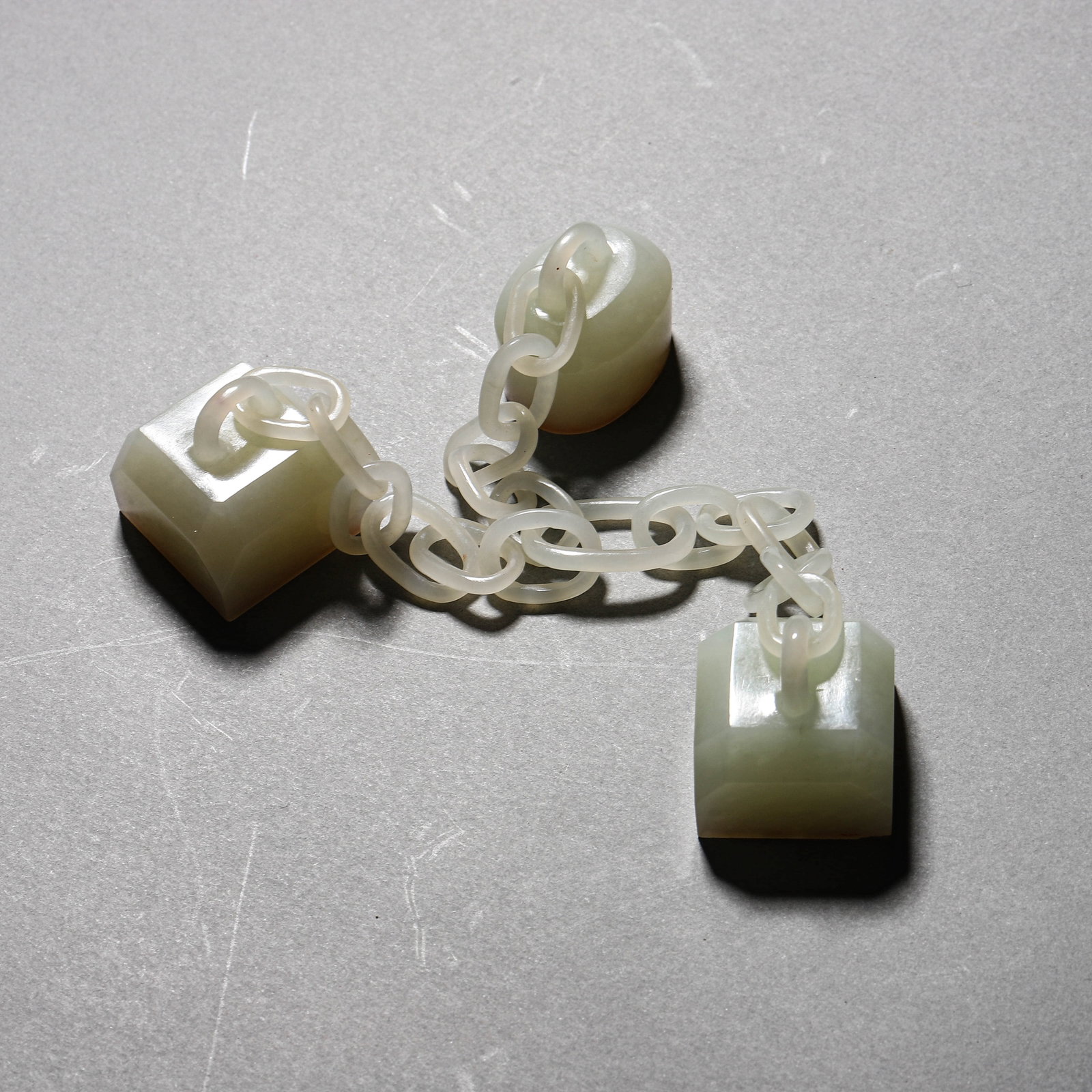 A WHITE JADE CHAINED TRIPLE SEAL: A WHITE JADE CHAINED TRIPLE SEAL Height: 1 1/16 in. (2.7 cm)