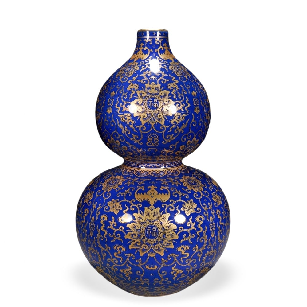 QIANLONG SACRIFICIAL-BLUE GLAZED GOURD-SHAPED VASE WITH GILT BLESSINGS AND LONGEVITY DECORATION: 12 5/8 x 6 3/4 in (32 x 17 cm) Qianlong Sacrificial-Blue Glazed Gourd-Shaped Vase with Gilt Blessings and Longevity Decoration Dimensions: H: 12 5/8 in (32 cm); W: 6 3/4 in (17 cm) This commanding