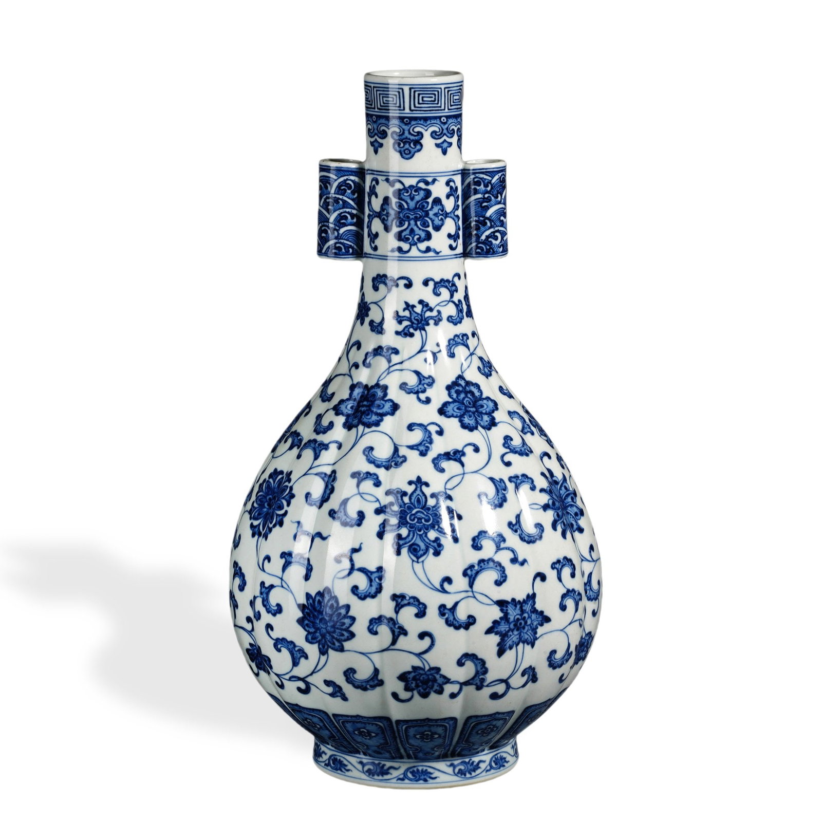 QIANLONG BLUE AND WHITE 'FLORAL SCROLL' MELON-LOBED TWIN-TUBE-HANDLED VASE: 16 7/8 x 8 5/8 in (43 x 22 cm) Qianlong Blue and White 'Floral Scroll' Melon-Lobed Twin-Tube-Handled Vase Dimensions: H: 16 7/8 in (43 cm); W: 8 5/8 in (22 cm) This commanding vase exemplifies the