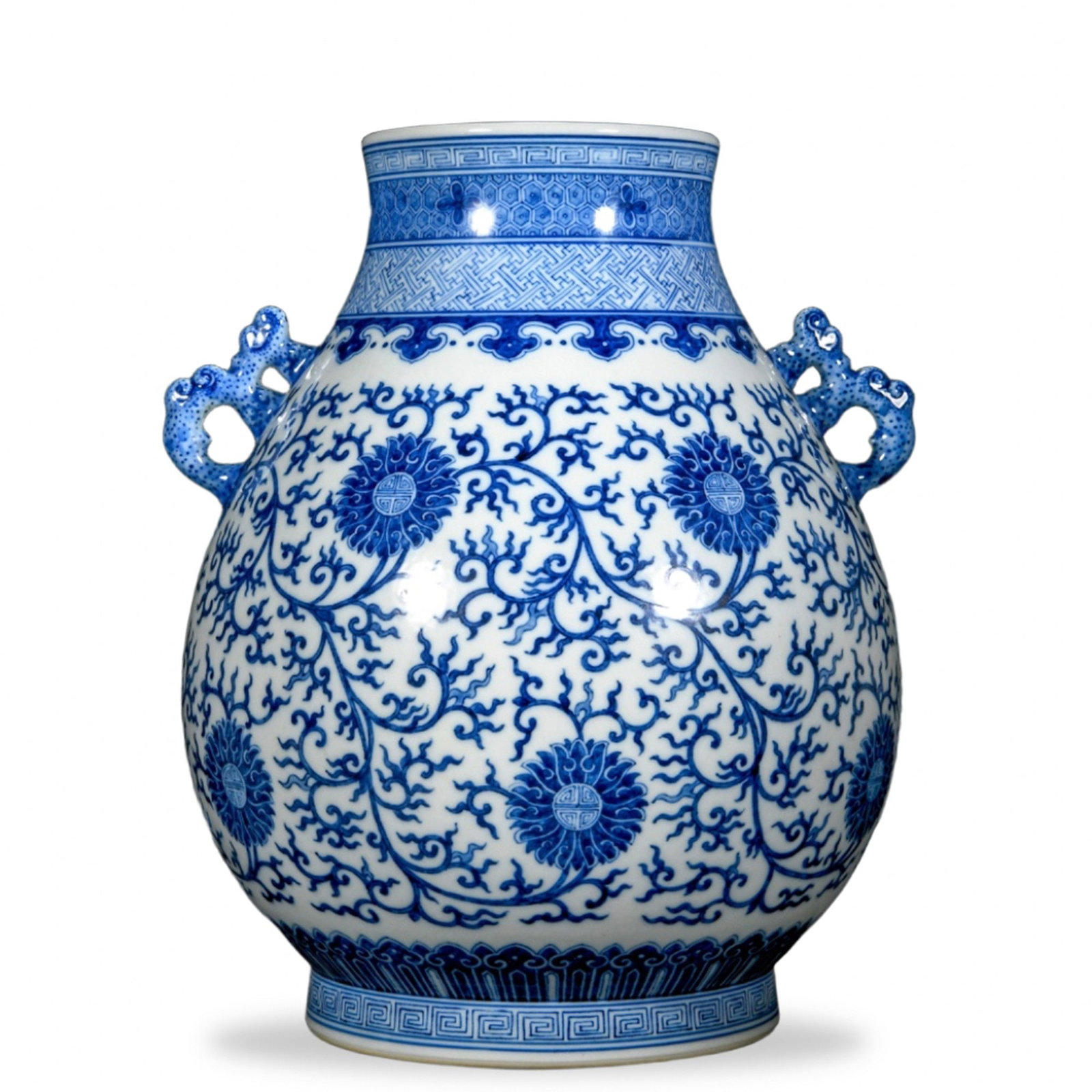 QIANLONG BLUE AND WHITE 'LOTUS SCROLL' ZUN WITH ELEPHANT-HEAD HANDLES: Qianlong Blue and White 'Lotus Scroll' Zun with Elephant-Head Handles Dimensions: H: 13 1/4 in (33.5 cm); W: 10 5/8 in (27 cm) This commanding zun embodies one of the most enduring archaistic forms