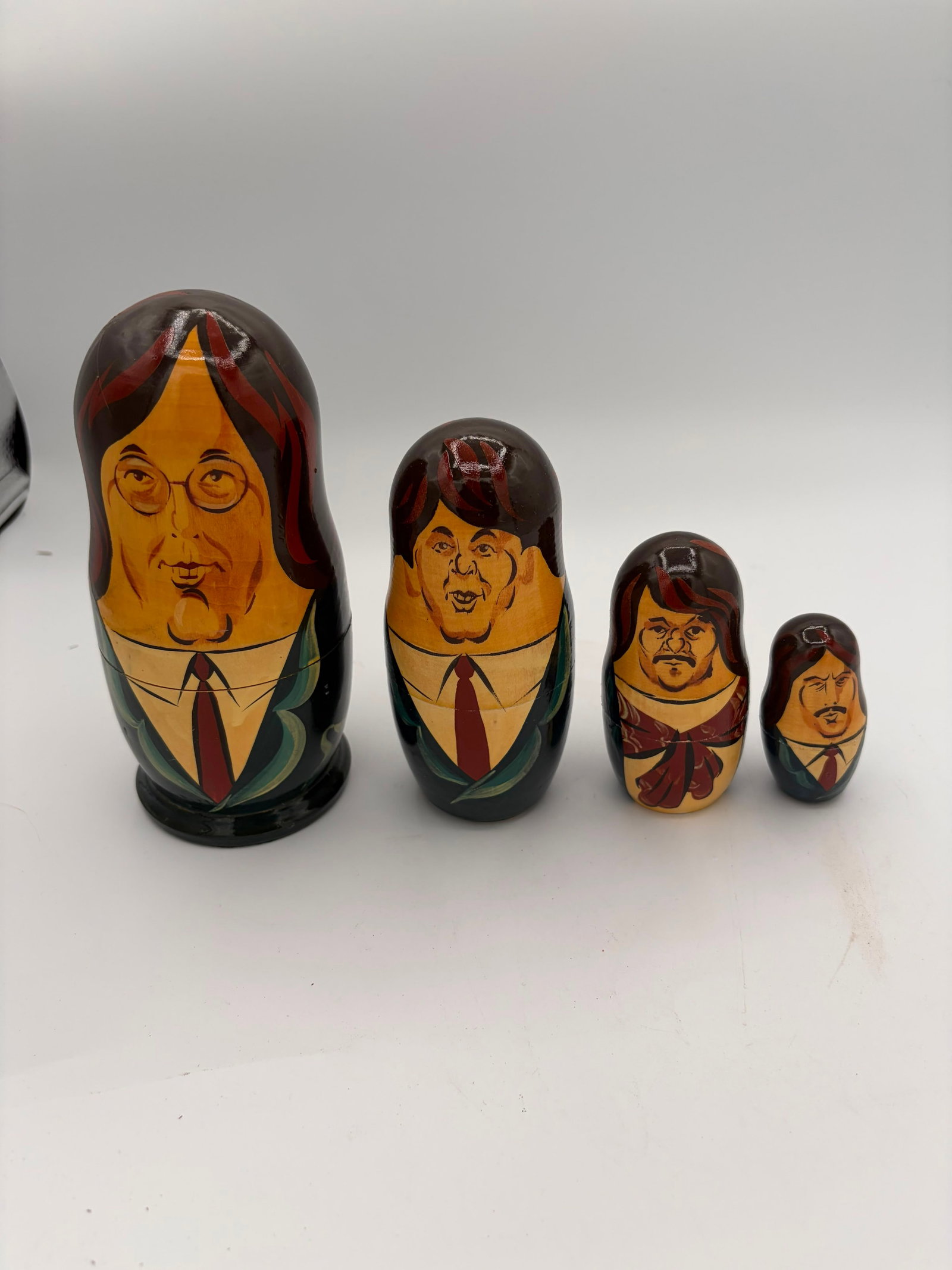 Hand Painted Wooden Russian Nesting Dolls Matryoshka Set of 4 Portrait Figures: Unique set of 4 hand-painted wooden Russian nesting dolls, also known as Matryoshka dolls, featuring detailed portrait-style faces and colorful clothing designs. The dolls nest inside one another and 