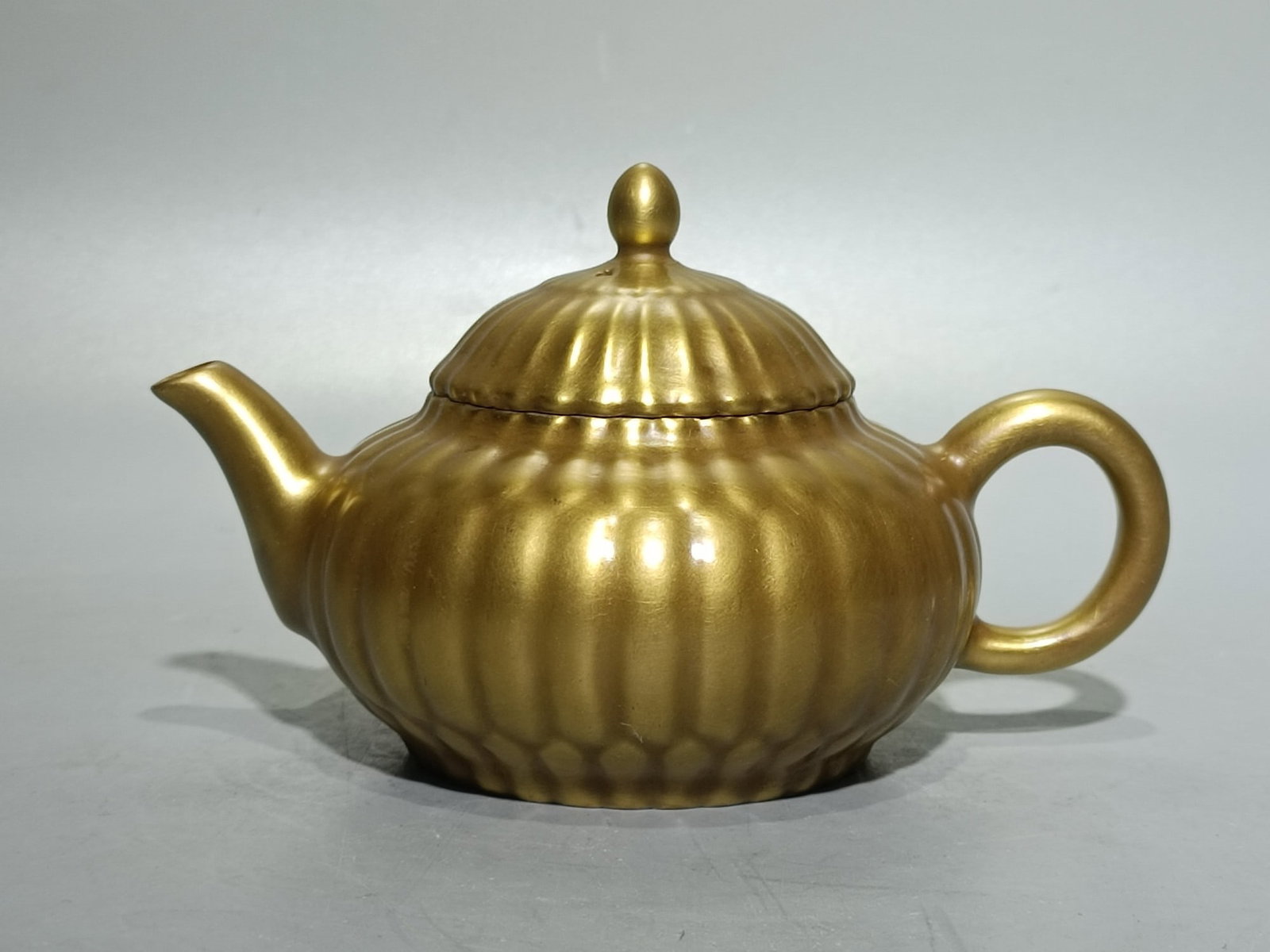 A gilt chrysanthemum petal teapot with the mark of the Yongzheng period of the Qing dynasty.: A gilt chrysanthemum petal teapot, bearing the mark of the Yongzheng period of the Qing dynasty. Height: 9cm, Width: 14.5cm. Thank you for viewing our auction and we look forward to serving you as a v