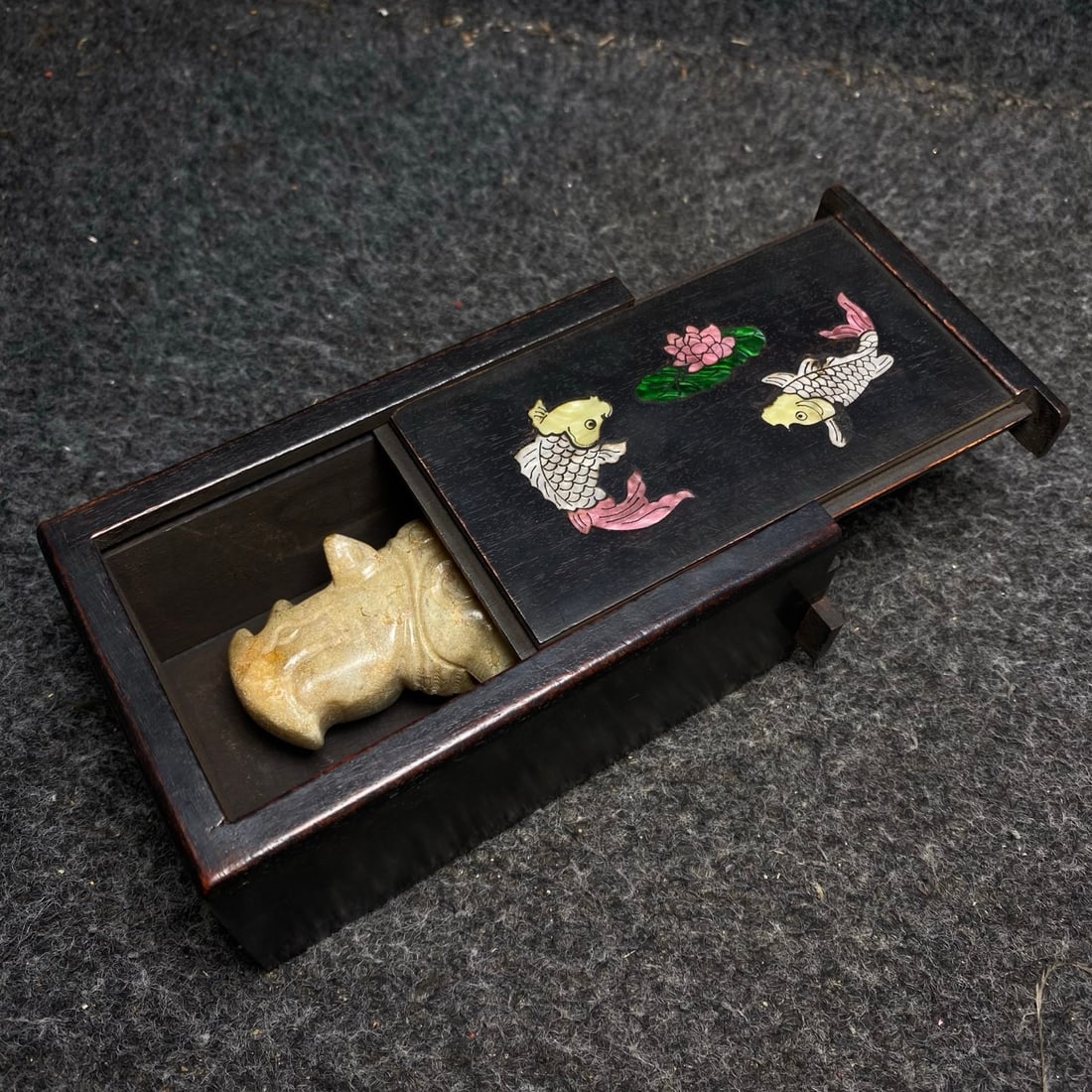 An ancient jade ornament is placed inside a rosewood and mother-of-pearl inlaid collection box.: A rosewood box inlaid with mother-of-pearl holds an antique jade ornament. Ornament dimensions: 8.5/3.5/5.5cm (L/W/H). Box dimensions: 13.5/8.6cm (L/W/H). Provenance:Private collection from a professo