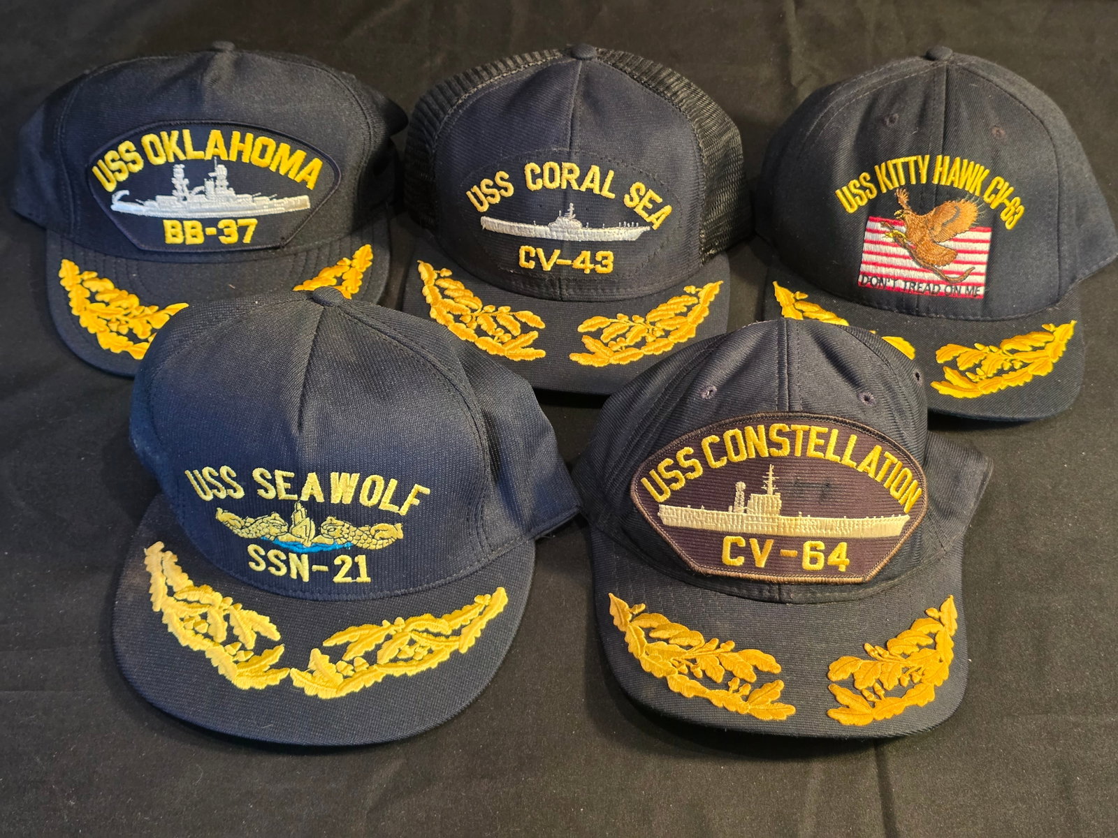 U.S. Navy Flag Officer Ball Cap Lot: USS Kitty Hawk (CV-63), USS Coral Sea (CV043), USS Oklahoma (BB-37), USS Constellation (CV-64), and USS Seawolf (SSN-21). 50% of all proceeds from the sale of this lot will be donated to the Raise You
