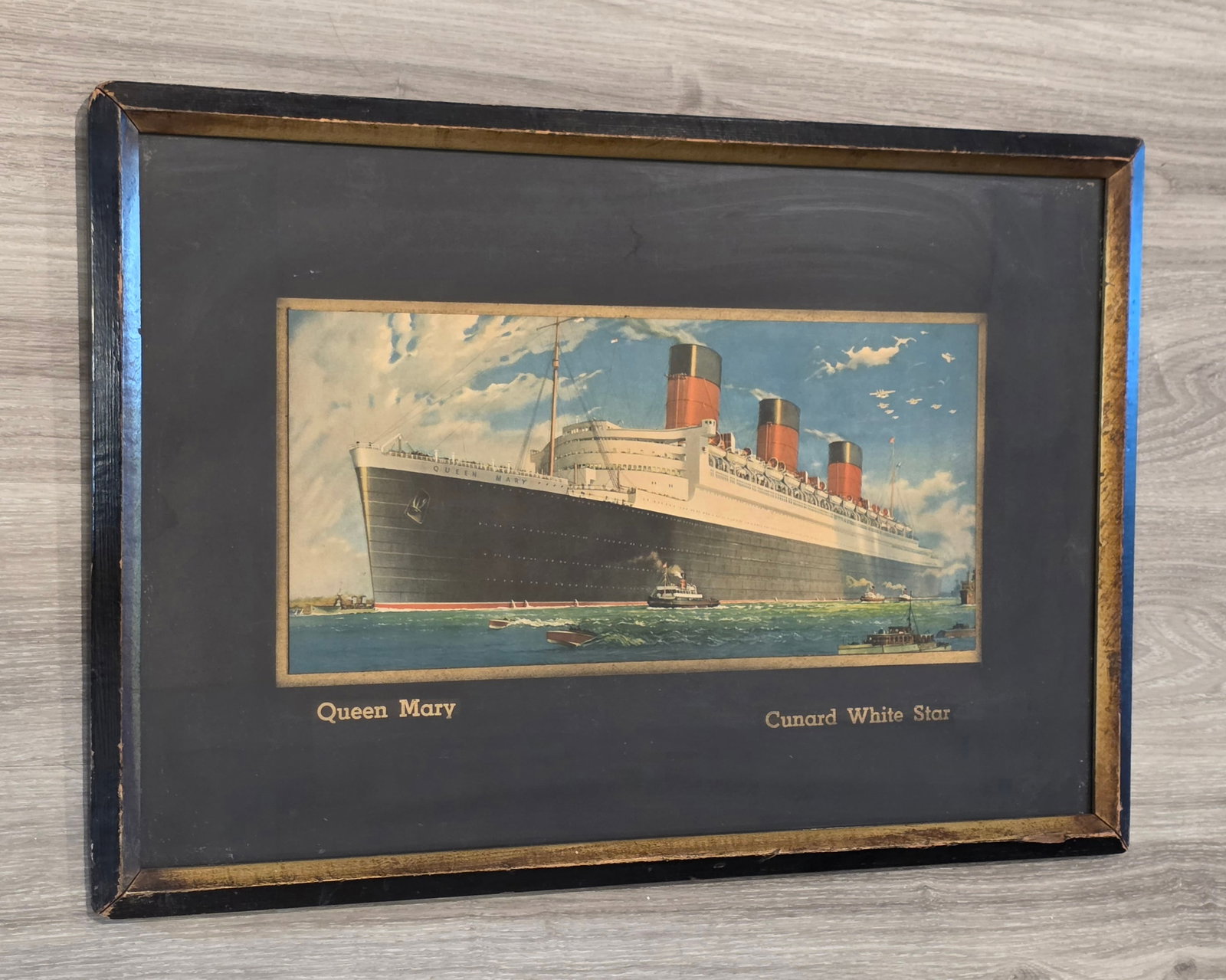 Cunard White Star R.M.S. Queen Mary Travel Agency Art: Color by William Mcdowell. Measures 25 1/2" 17 3/4", inner print measures 7 3/4" x 17". Undated. 50% of all proceeds from the sale of this lot will be donated to the Raise Your Banner Foundation, a Wa