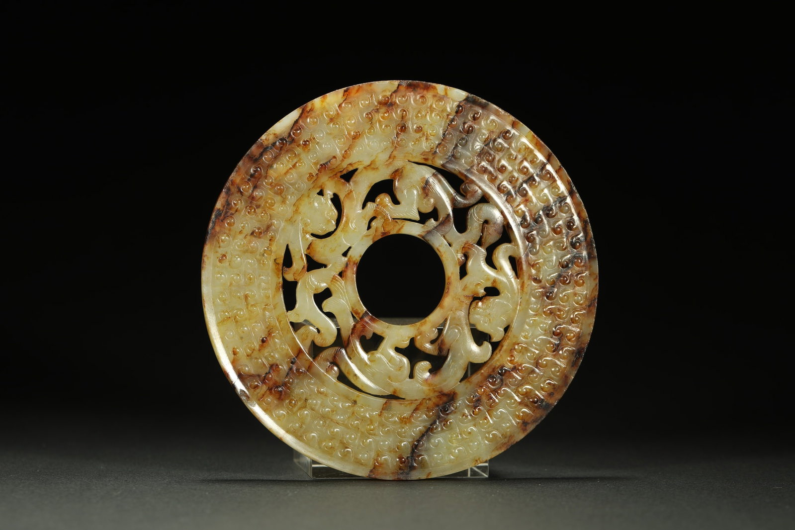 HETIAN JADE BI DISC: Dimensions: Diameter 4 1/2 in; weight 95 g This Hetian jade bi disc presents a refined and understated elegance through its balanced circular form and richly textured natural surface. The concentric