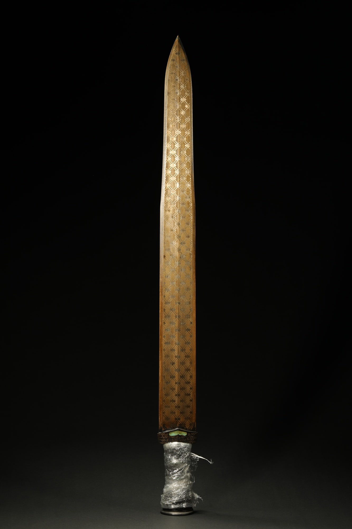 BRONZE GILT-SILVER SWORD: Dimensions: 25 5/8 in; weight 1338 g This bronze gilt-silver sword presents a commanding ceremonial elegance through its elongated blade and richly ornamented decorative surface. The straight,