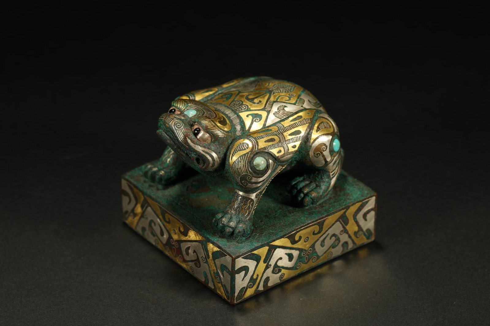 BRONZE GILT-SILVER SEAL: Dimensions: 2 1/2 x 2 1/2 in; weight 645 g This bronze gilt-silver seal presents a powerful ceremonial character through its compact architectural form and finely sculpted beast finial. The crouching 