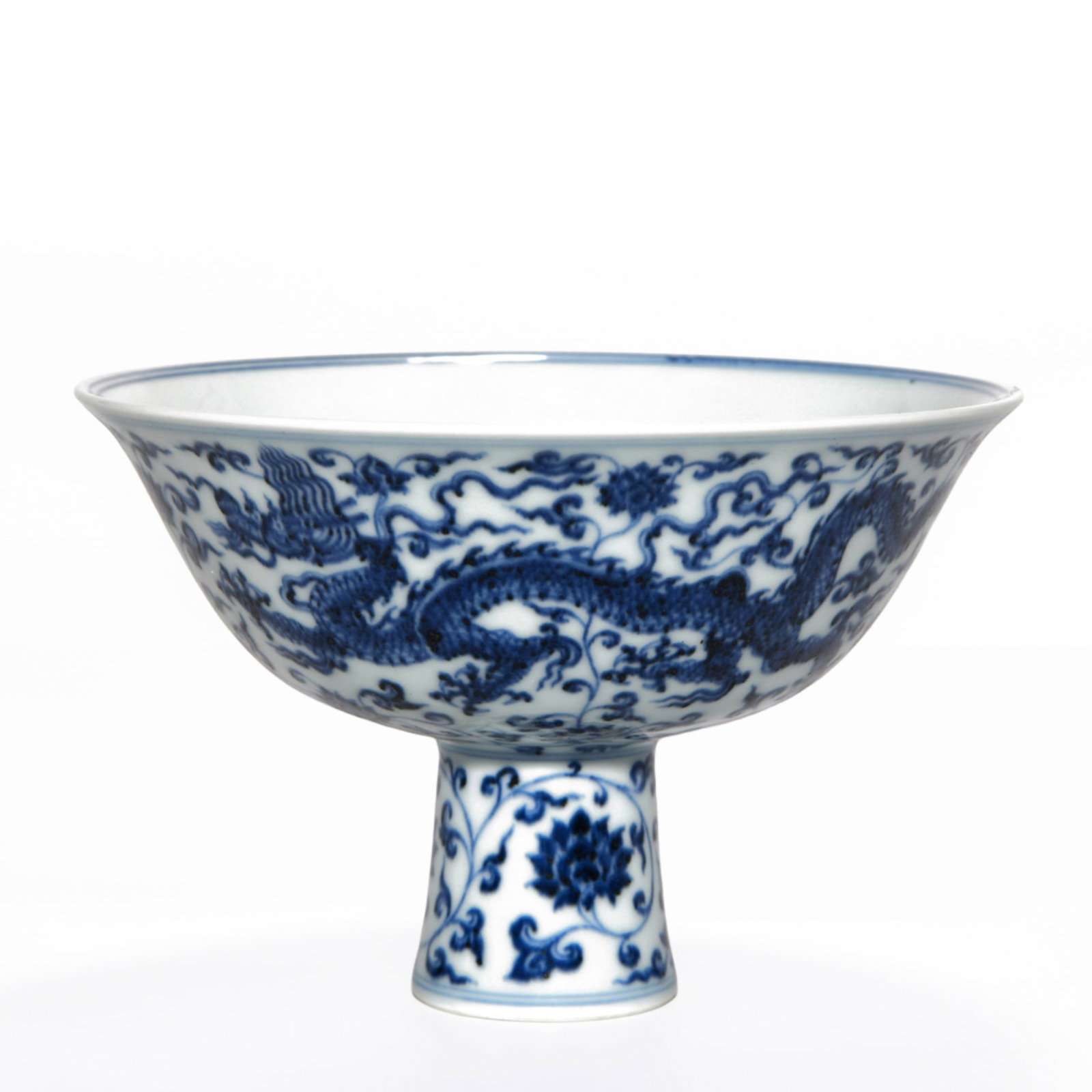 XUANDE PERIOD BLUE AND WHITE DRAGON STEM BOWL: Dimensions: 4 3/8 x 6 3/4 in A blue and white stem bowl from the Xuande period, decorated around the exterior with a dragon in pursuit of a flaming pearl, rendered in underglaze cobalt blue. The bowl