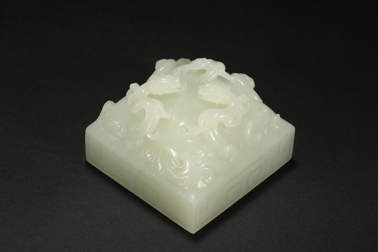 HETIAN JADE SEAL: Dimensions: 3 1/2 x 2 1/8 x 2 1/8 in; weight 214 g This Hetian jade seal presents a refined architectural form enriched by delicate relief carving and the natural elegance of pale jade. The square