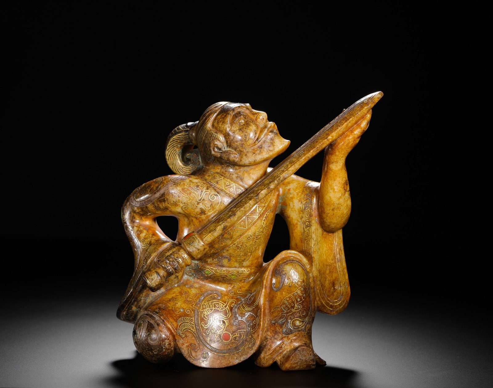 HAN DYNASTY HETIAN JADE FIGURINE OF A MUSICIAN INLAID WITH GOLD AND GEMSTONES: H:17cm(6.69in)W:16cm(6.30in)Weight:1890g(4.17lb)The figurine is carved in the round as a seated musician playing an instrument. The clothing and patterns are decorated with gold inlay and gemstone acc