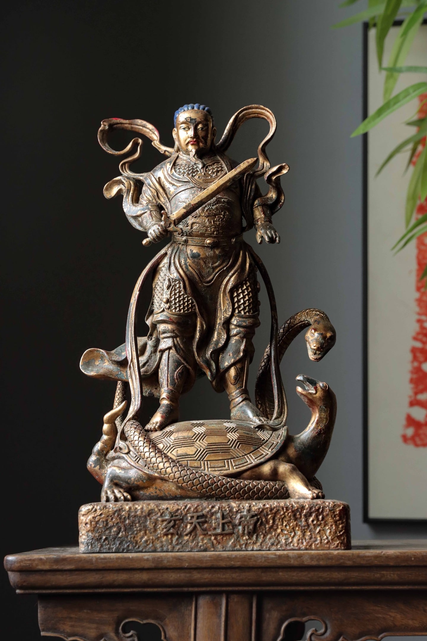 A GILDED BRONZE STATUE OF EMPEROR ZHENWU FROM THE QING DYNASTY: Weight:4500g (9.92lb) H:40cm (15.75in) W:22cm (8.66in) T:15cm (5.91in)Cast copper with lacquer gilding; deity stands atop Xuanwu tortoise-snake creature holding seven-star sword, pedestal carved with 
