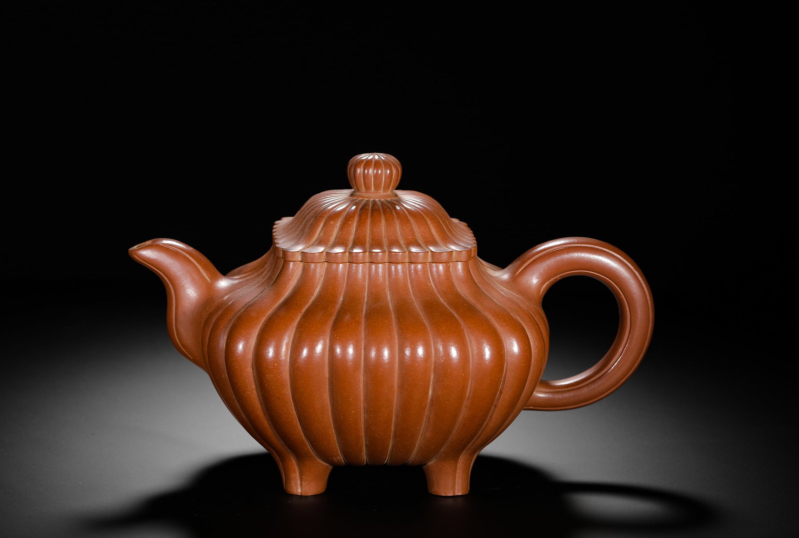QING DYNASTY PURPLE CLAY FOUR-LEGGED TEAPOT WITH CHRYSANTHEMUM PETAL PATTERNS: H:19cm(7.48in)W:26cm(10.24in)Weight:1080g(2.38lb)The vessel is a four-footed teapot with a chrysanthemum petal pattern. The lid knob is also shaped like a chrysanthemum, matching the body. The pot is 