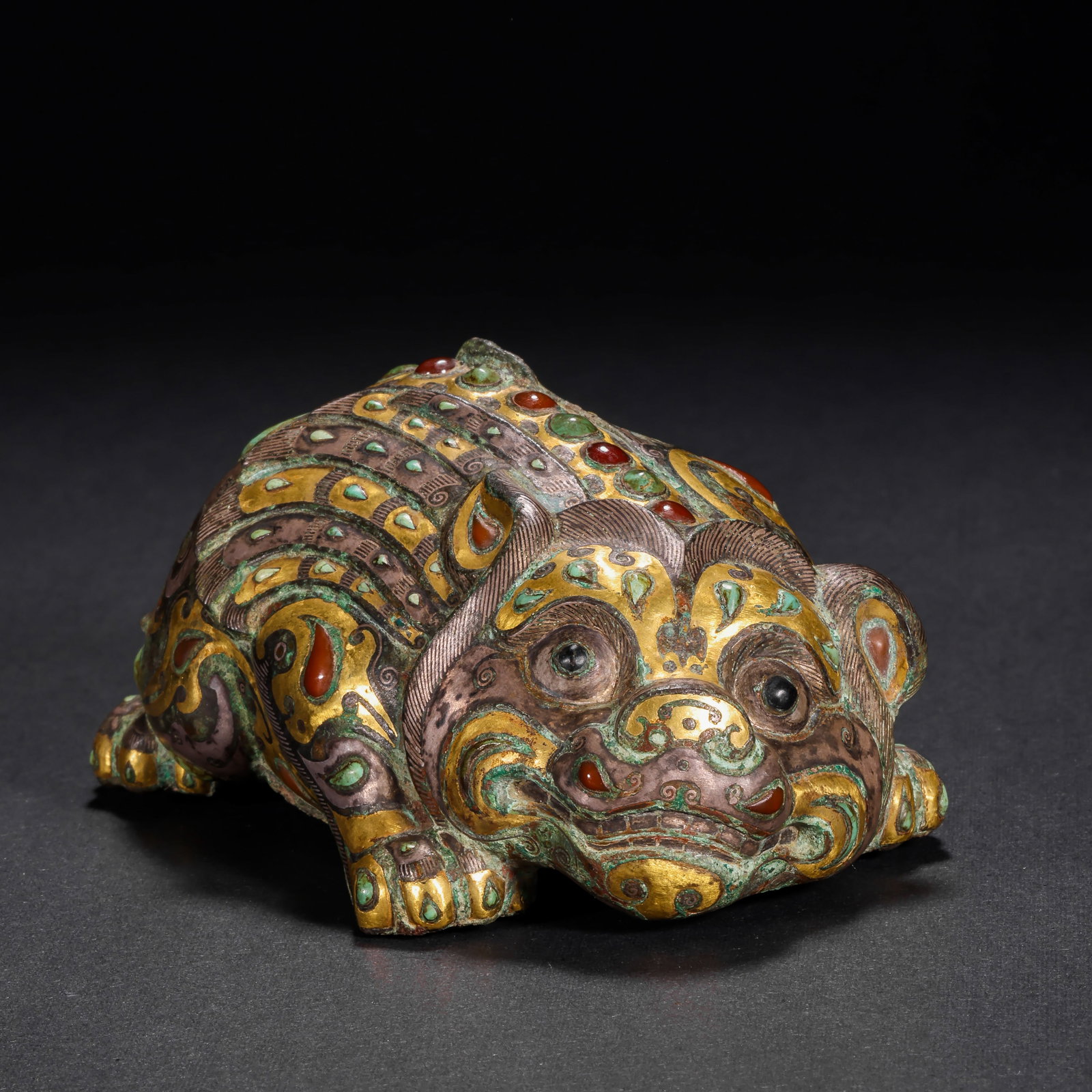 HAN DYNASTY COPPER INLAID GOLD AND SILVER INLAID GEMSTONE AUSPICIOUS BEAST TOWN: H:4cm(1.57in) W:10cm(3.94in) Weight:460g(1.01lb)This artifact is cast in bronze, fully decorated with patterns on the beast's body using gold and silver inlay technique, inlaid with red and green gems