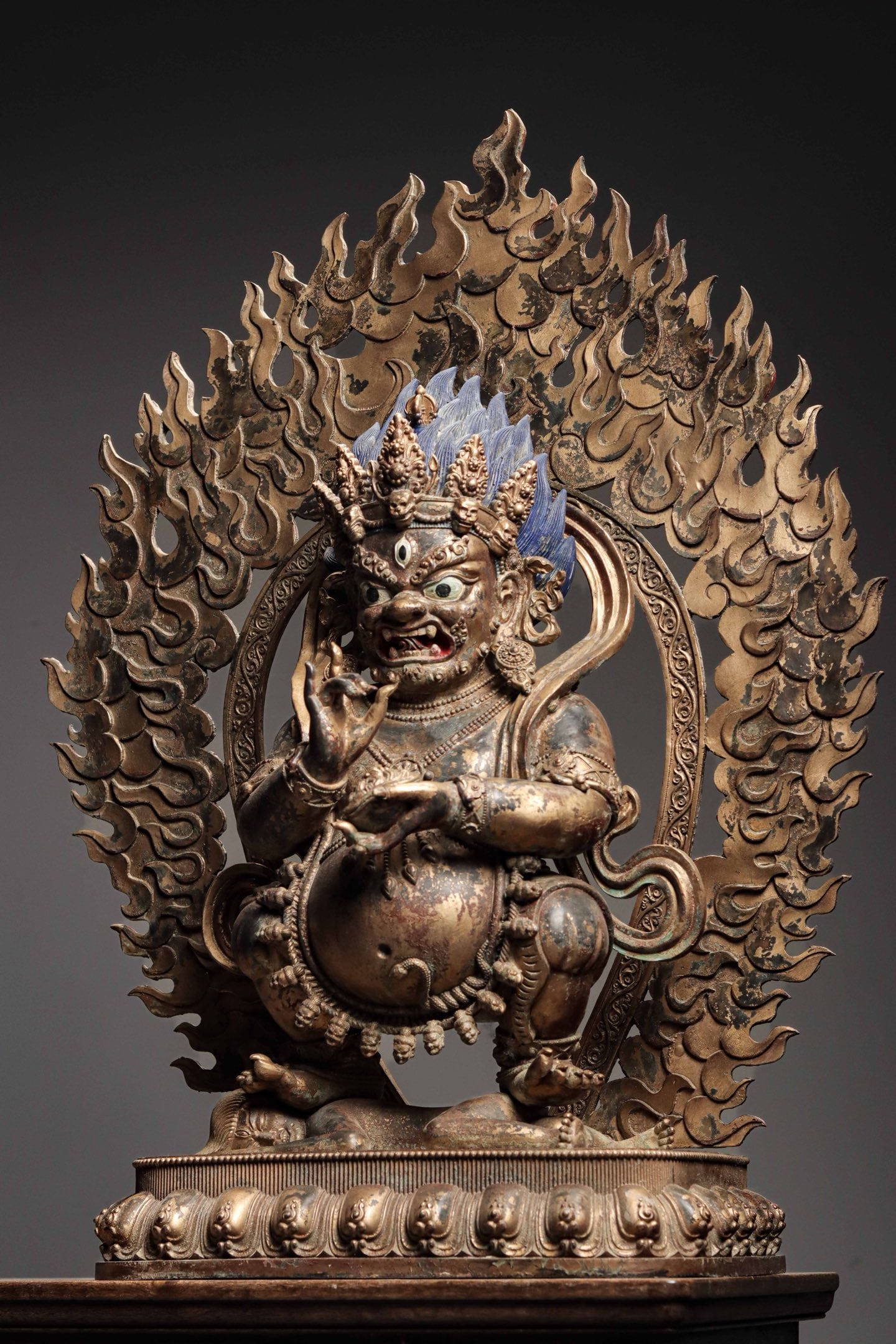A GILDED BRONZE STATUE OF THE GREAT BLACK SKY FROM THE QING DYNASTY: Weight:27000g (59.52lb) H:80cm (31.50in) W:41cm (16.14in) T:25cm (9.84in)Solid cast bronze with mineral blue pigment on hair and partial surviving gilding: hollow-cut flaming aureole, squatting on lot