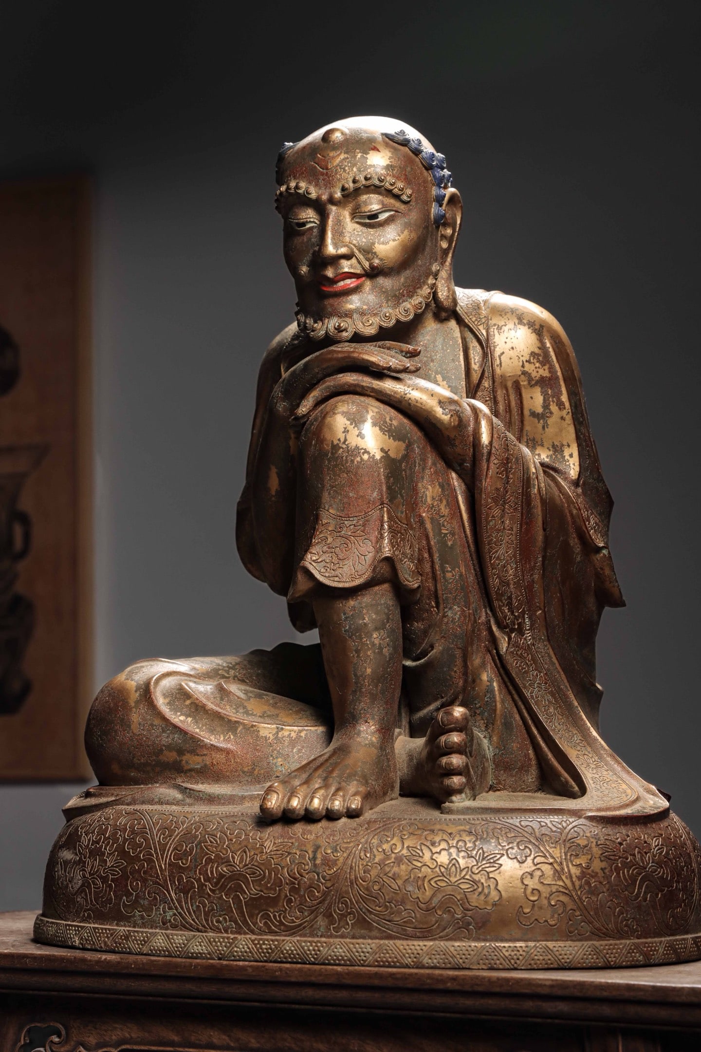 A GILDED BRONZE STATUE OF THE GREAT SCHOLAR OF THE SNOW MOUNTAIN FROM THE MING DYNASTY: Weight:23300g(51.37lb)H:66cm(25.98in)W:52.6cm(20.71in)T:44cm(17.32in)With arms crossed and resting on knee, it has a leisurely relaxed figure with naturally draped robe carved with delicate hidden scr