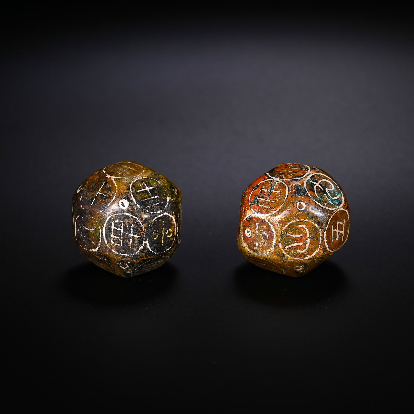 PAIRS OF BRONZE DODECAHEDRAL BORONS FROM THE HAN DYNASTY: D:1.8cmWeight:70gPair of silver-inlaid bronze twelve-sided Boqiong, Han Dynasty. The bronze bodies are covered with mixed red and green ancient patina. Each facet is enclosed in a circular frame with 