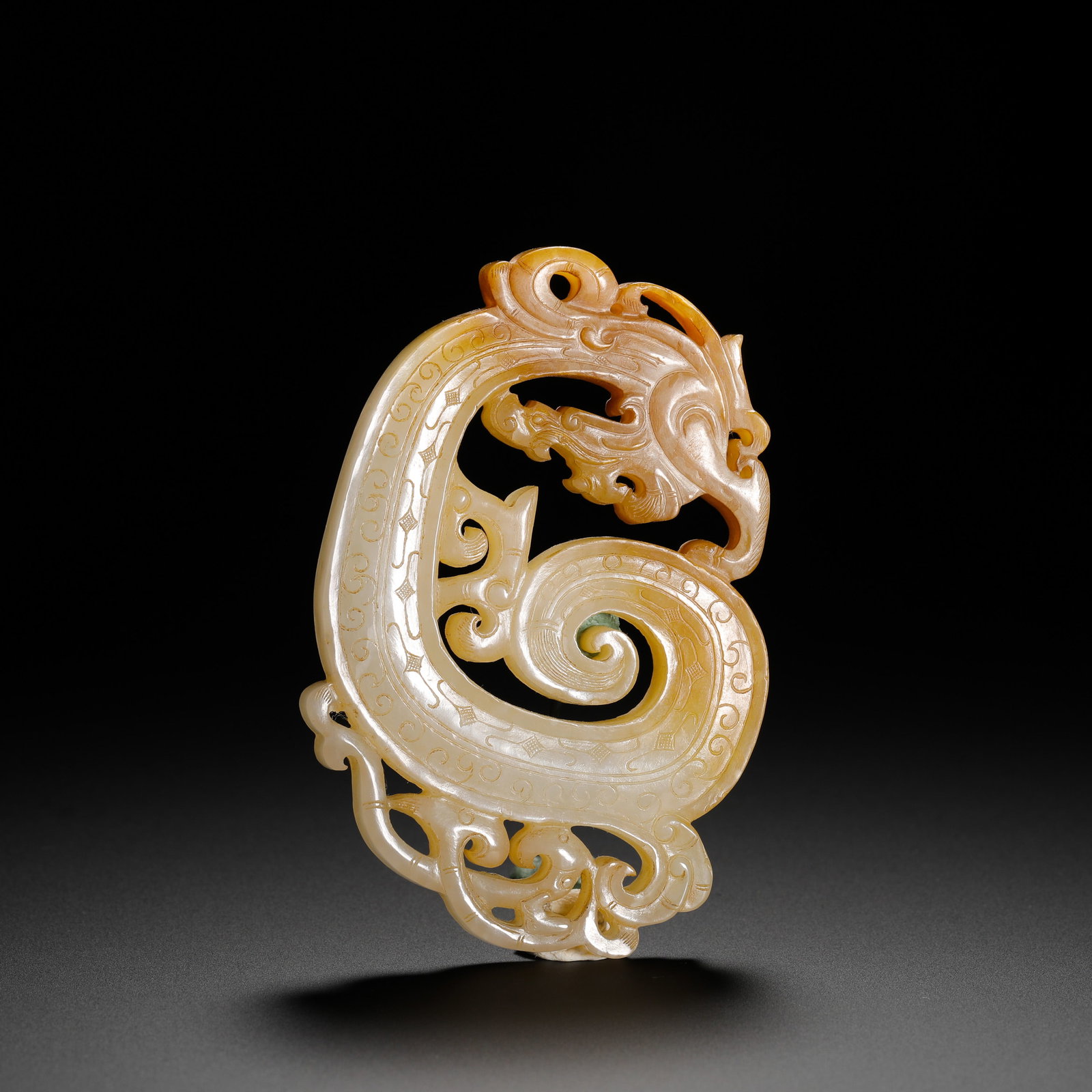 HETIAN JADE DRAGON AND PHOENIX PIERCED CARVING PENDANT FROM THE WARRING STATES PERIOD: Height:8.5cm(3.35in) Width:5.5cm(2.17in) Weight:65g(0.14lb)Warring States Hetian jade openwork dragon-phoenix pendant, shaped as coiled S-dragon with small phoenix carved below. Full grain and rhombus