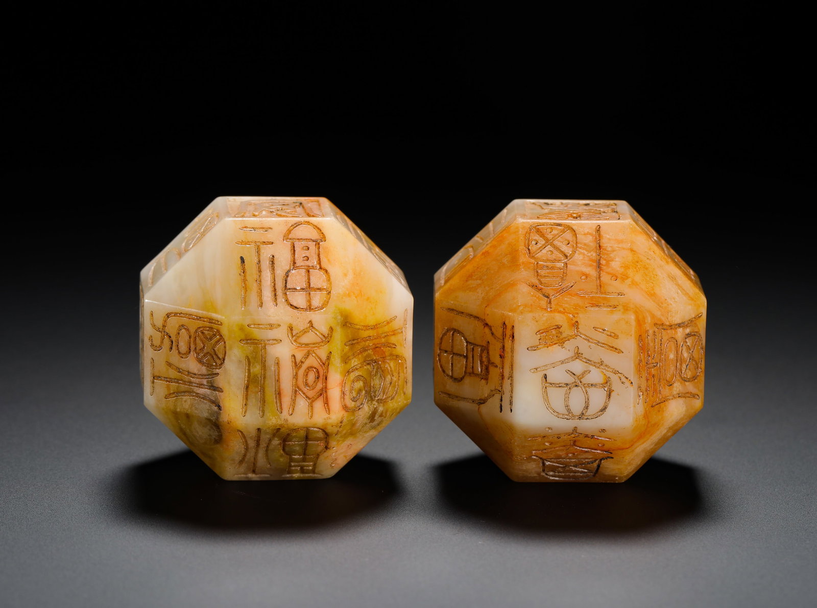 A PAIR OF HETIAN JADE AUSPICIOUS DICE FROM THE HAN DYNASTY: D:4cm(1.57in) Weight:240g(0.53lb)A pair of Han Dynasty twelve-sided auspicious-word dice carved from Hetian white jade with earth stains. The jade is mottled with yellow-brown and yellow-green burial 