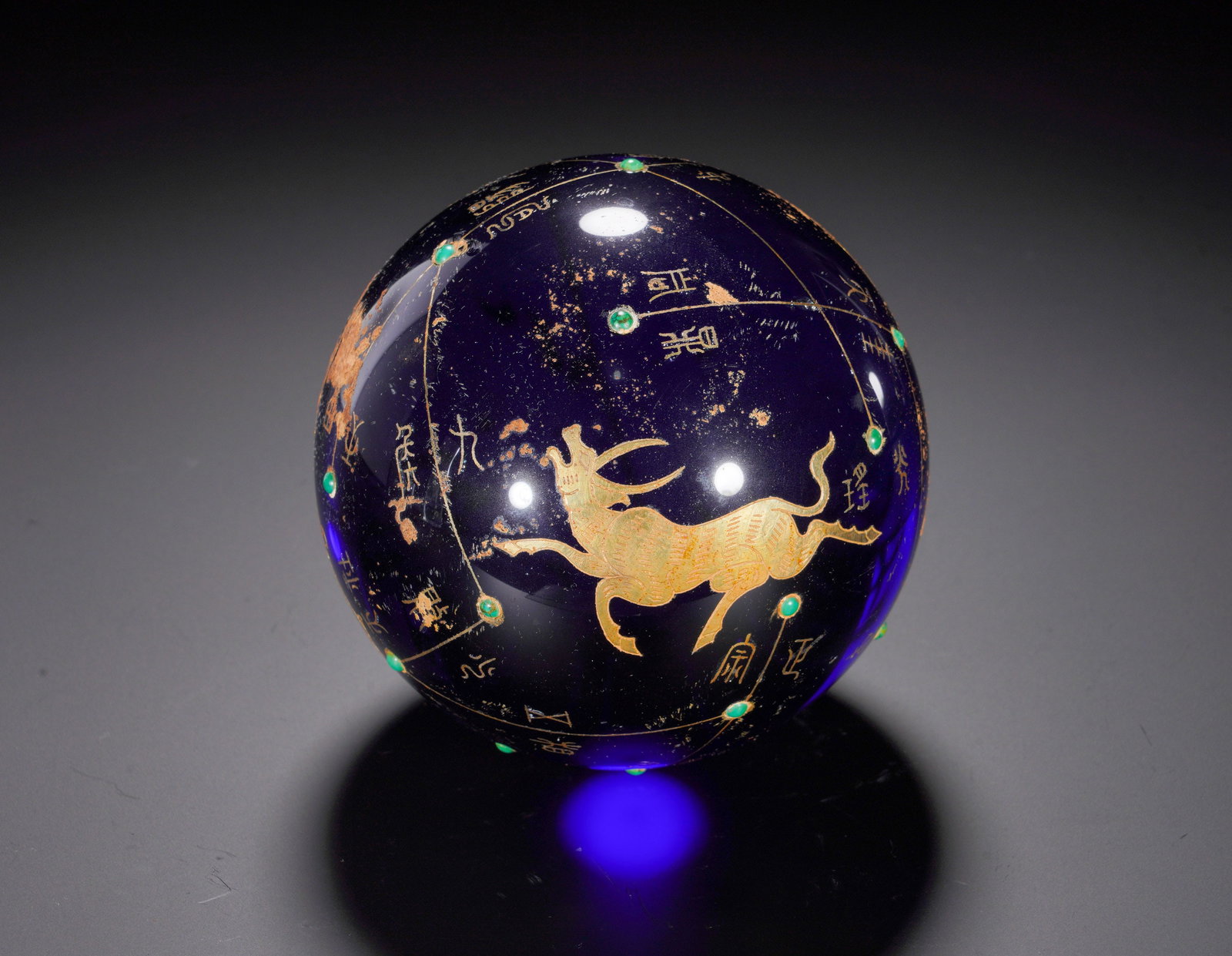 A HAN DYNASTY GLAZED BALL WITH GOLD INLAID WITH TURQUOISE AND STAR-SHAPED BULL RUNNING PATTERN