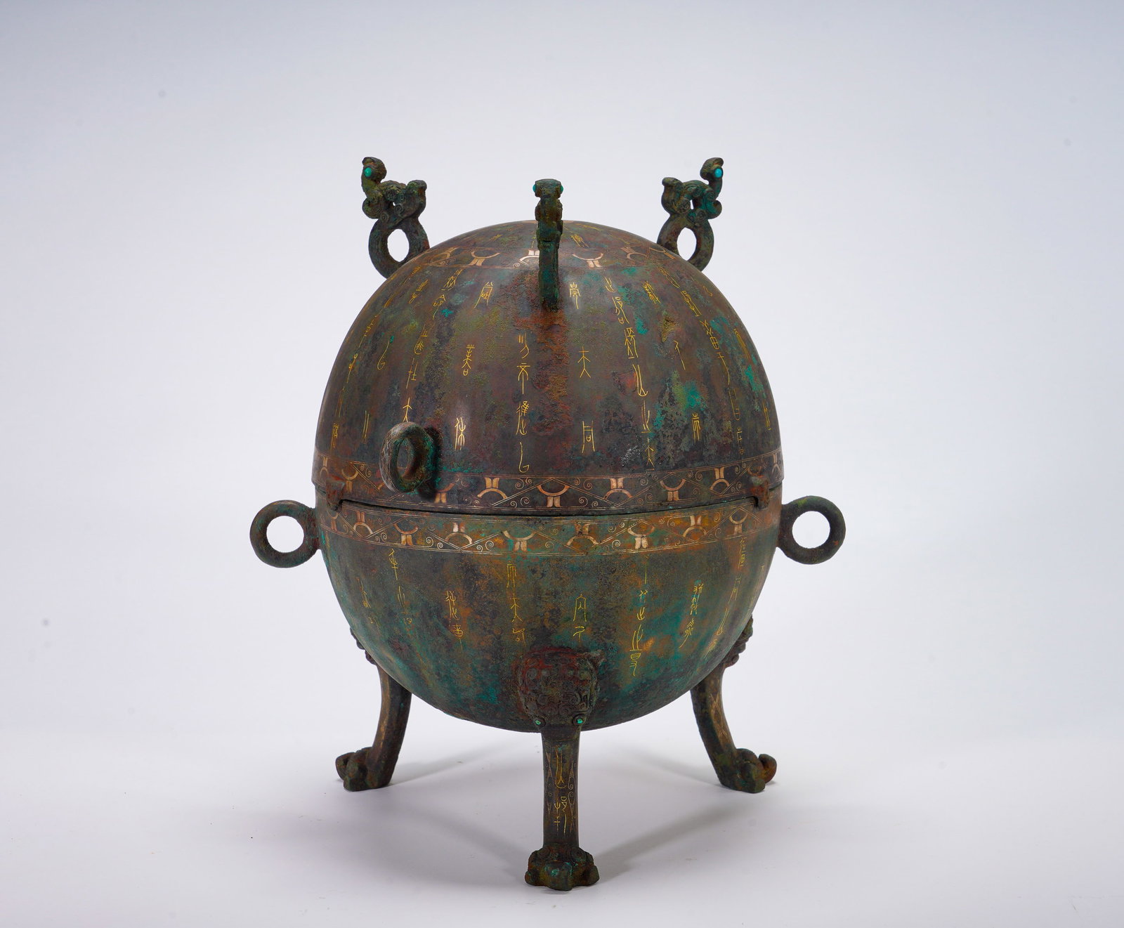 BRONZE FROM THE WARRING STATES PERIOD WITH GOLD INSCRIPTIONS ON THE THREE-LEGGED TUN: Height:29cm(11.42in) Width:25cm(9.84in) Weight:3010g(6.64lb)The spherical bronze dun with lid supported by three beast feet, phoenix bird knobs on cover. Long ancient texts inlaid by gold wire around