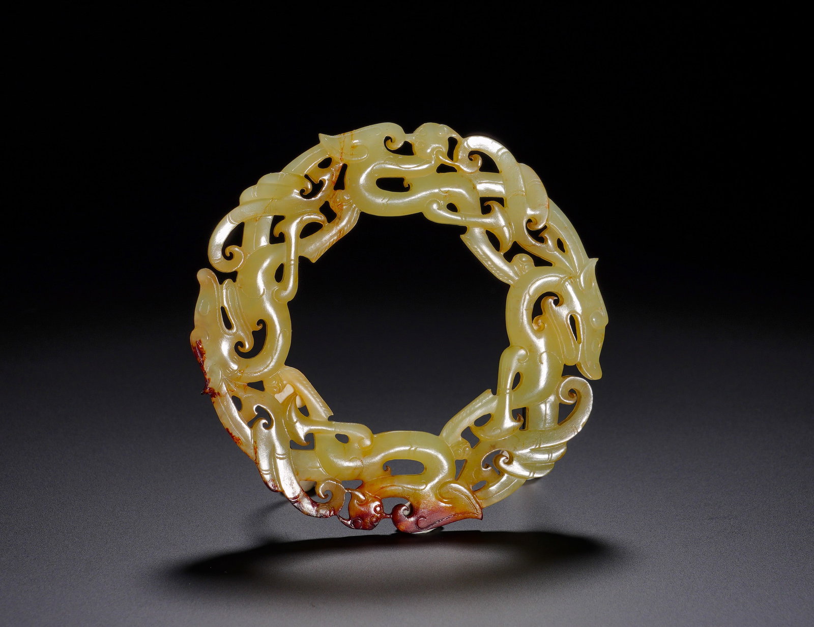 HAN DYNASTY HETIAN JADE DRAGON-PATTERNED RING: Height:8cm(3.15in) Width:8cm(3.15in) Weight:30g(0.07lb)Yellowish jade circular pendant carved with interwoven dragons forming continuous loop. Natural russet patina. Dragon symbolizes eternal vitality