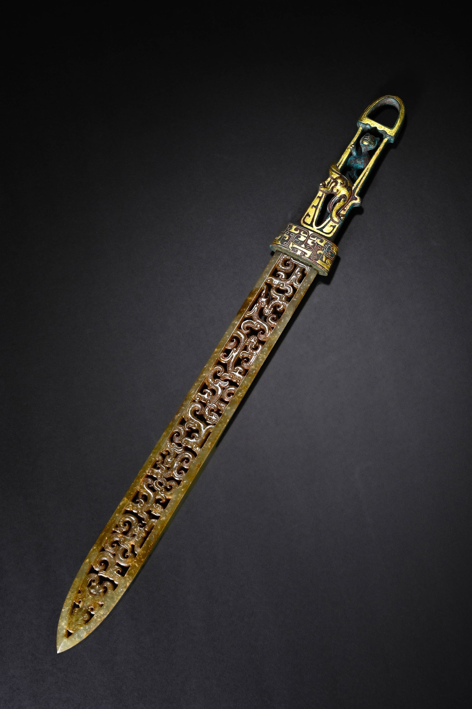 BRONZE GILDED SWORD HEAD WITH PIERCED DRAGON AND PHOENIX PATTERNS FROM THE HAN DYNASTY: This is a high-grade ritual jade sword of the Han Dynasty. The blade is carved from Hetian jade with mellow texture and ancient patina all over. The whole blade adopts sophisticated openwork carving t