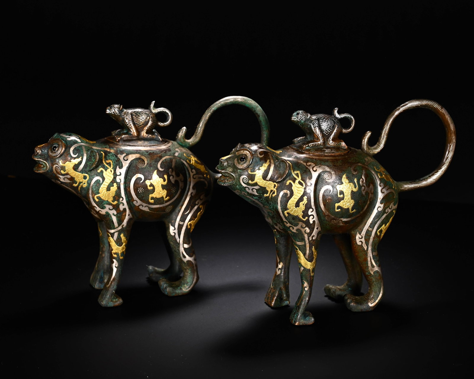 BRONZE INLAID GOLD AND SILVER AUSPICIOUS BEAST VASE FROM THE WARRING STATES PERIOD (PAIR): Warring States Period, Pair of Bronze Beast Vessels Inlaid with Gold and SilverMatched bronze pair. Fierce beast form with spout at mouth, four legs, coiled tail, monkey knob on lid. Fully decorated w