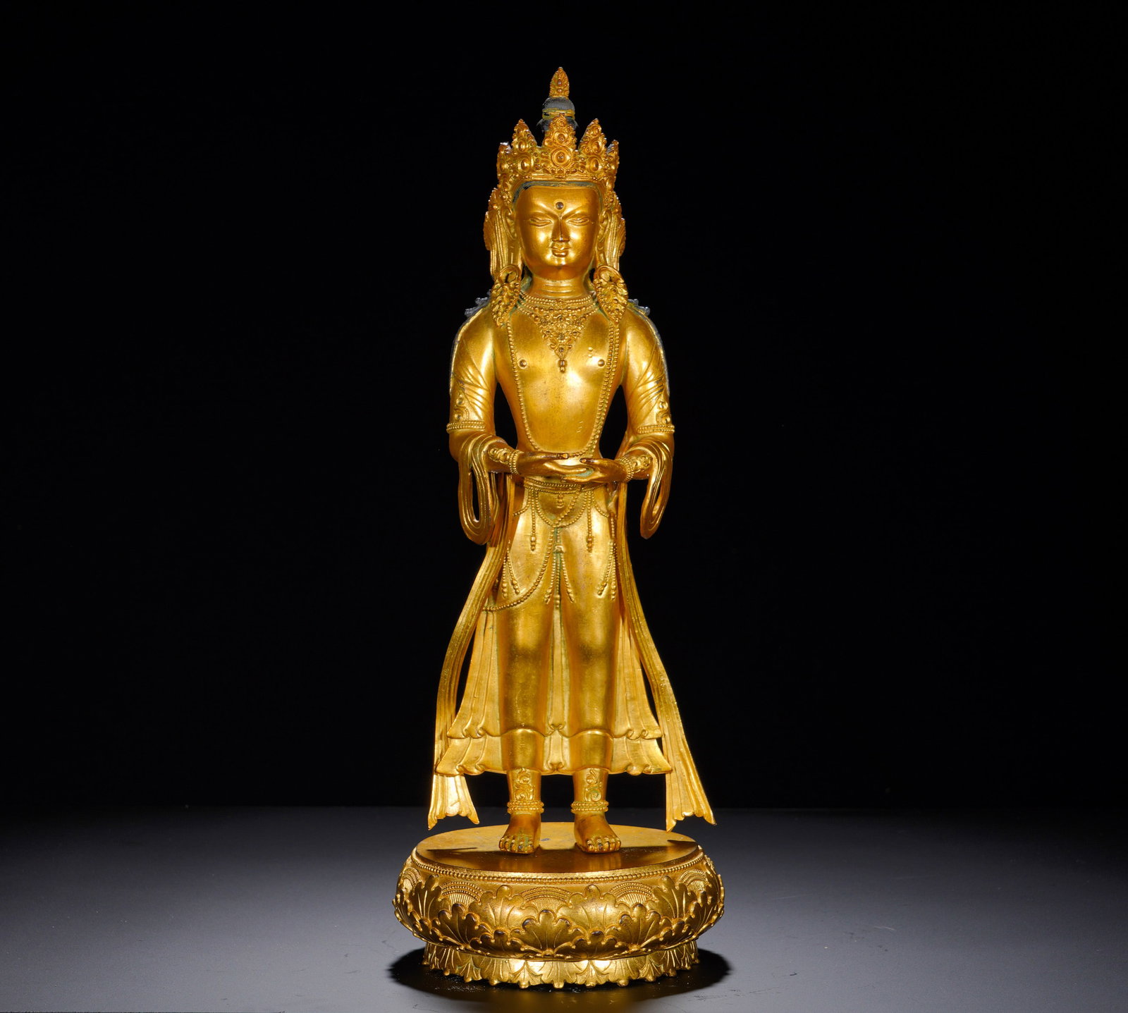 A STANDING STATUE OF THE BUDDHA OF INFINITE LIFE IN GILDED BRONZE FROM THE MING DYNASTY: Height: 46cm(18.11in), Width: 17cm(6.69in), Weight: 5510g (12.148lb)Amitayus embodies boundless lifespan and purity. Standing examples are rarer than seated versions. With upright balanced proportions