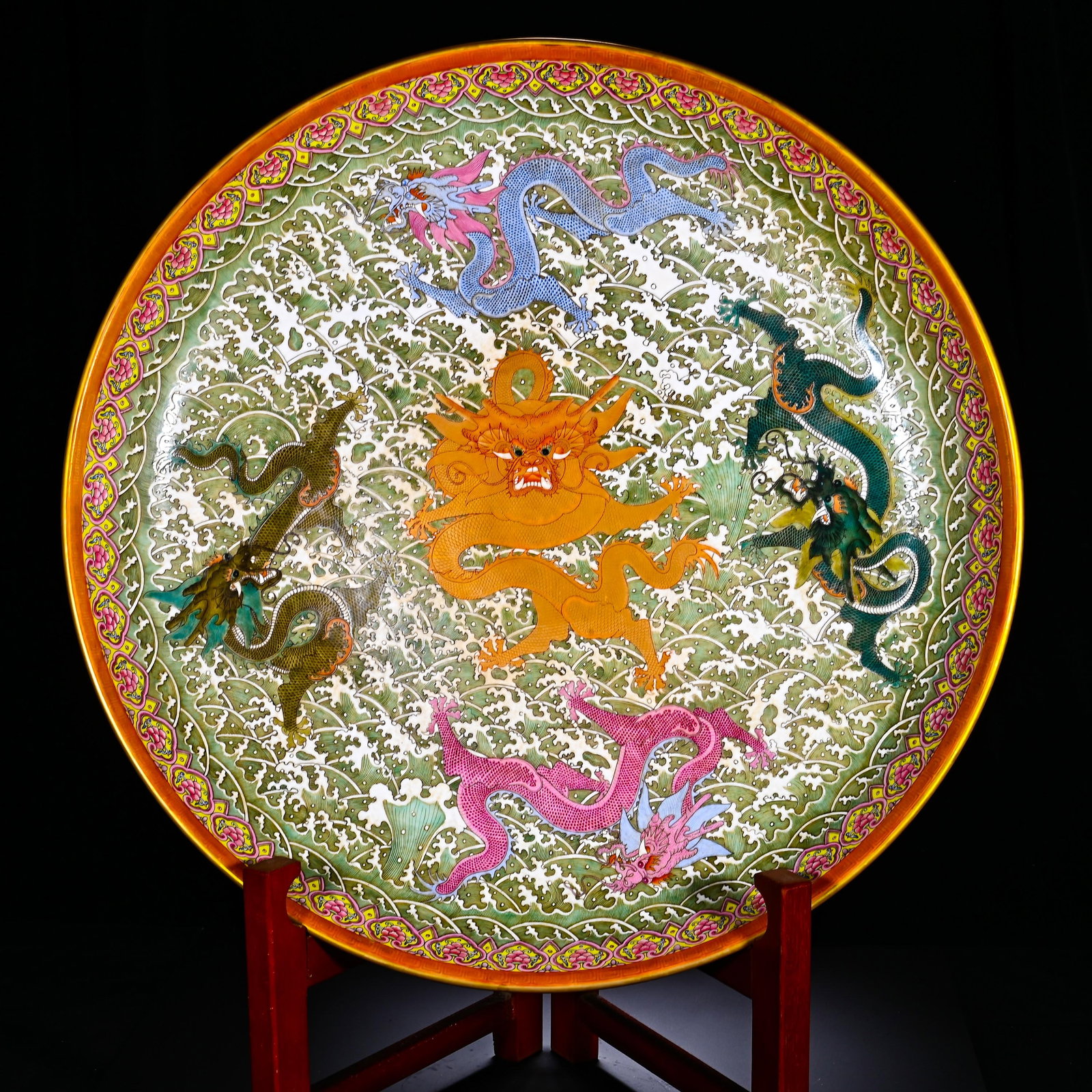A LARGE PLATE OF THE QING DYNASTY QIANLONG PASTEL PATTERN OF FIVE DRAGONS IN THE SEA: Height: 9cm(3.54in), Diameter: 59cm(23.23in)This is a large Qianlong?period famille?rose dish with seawater?and?five?dragon motifs. Wide flared gilded rim adorned with scrolling?floral border. The int