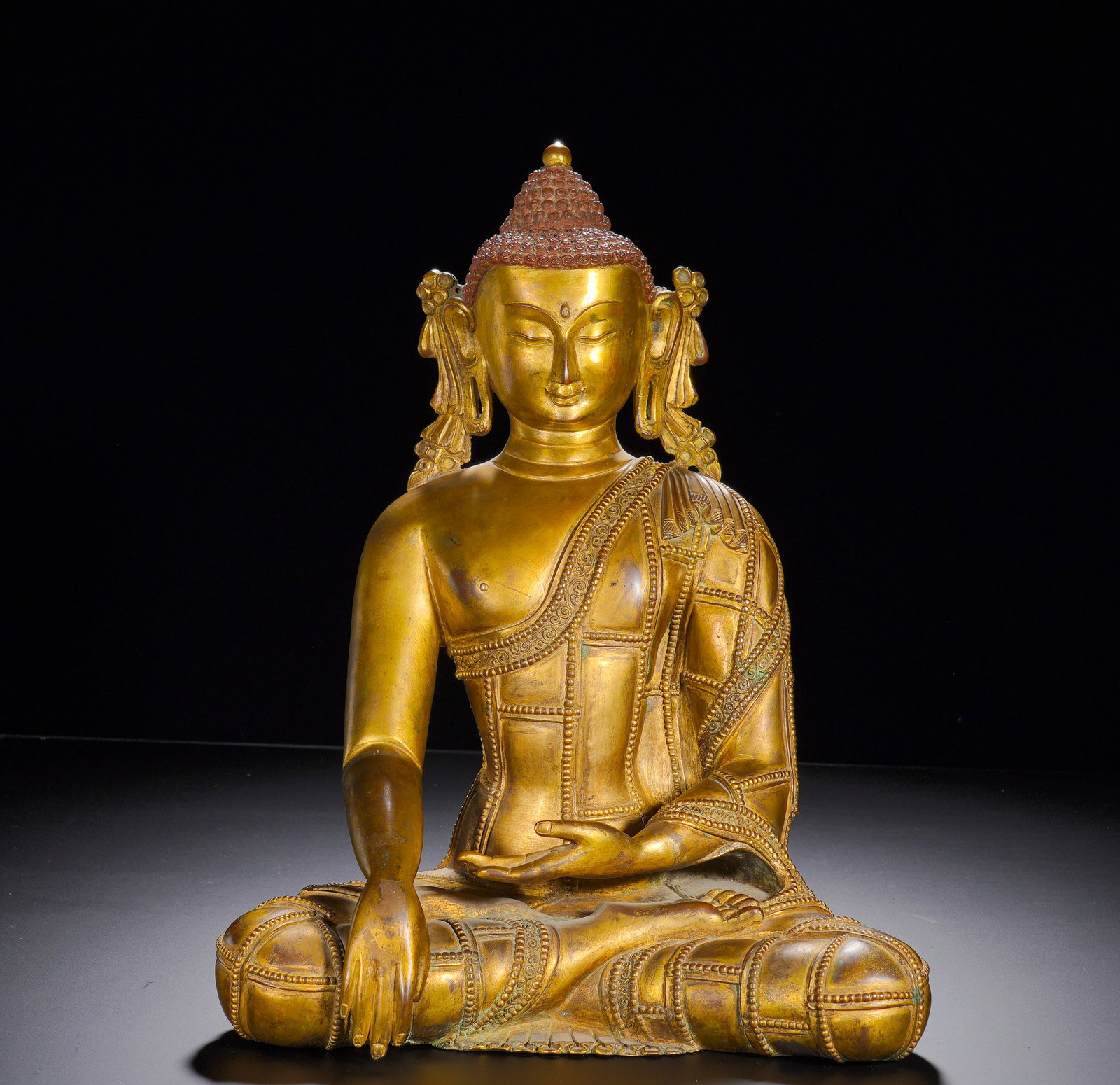 A GILDED BRONZE STATUE OF SAKYAMUNI BUDDHA ATTAINING ENLIGHTENMENT FROM THE MING DYNASTY: Height: 32cm(12.60in), Width: 26cm(10.24in), Weight: 6200g (13.669lb)Enlightenment Shakyamuni belongs to the most established category of Buddhist bronzes, symbolising overcoming afflictions and spiri