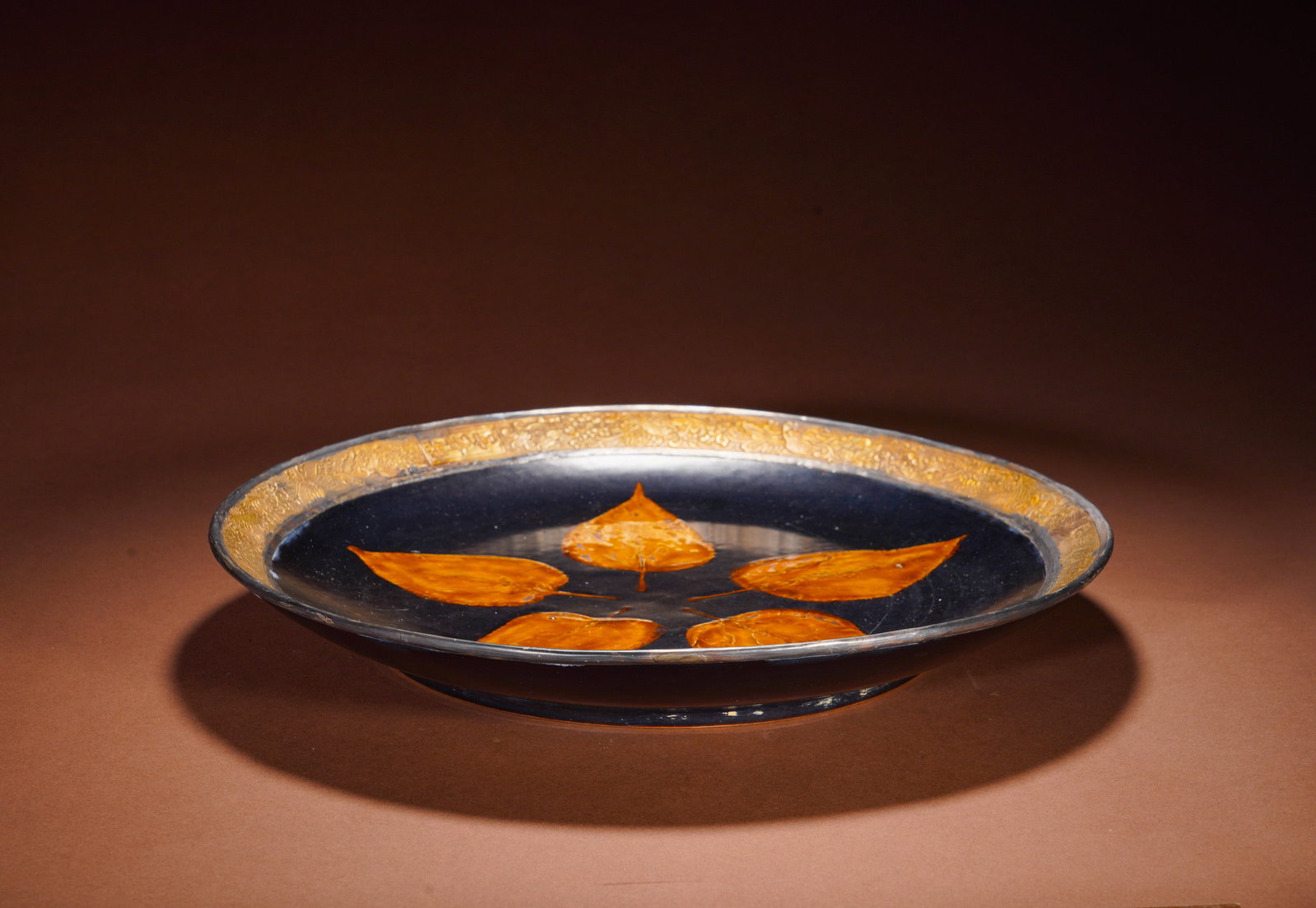 BLACK GLAZED FOLDED RIM LARGE PLATE FROM JIZHOU KILN OF THE SONG DYNASTY: Height: 5.5cm(2.17in), Diameter: 35cm(13.78in), Weight: 1900g (4.189lb)This shallow wide-rim plate is a masterpiece of Song Jizhou kiln. Fully covered in glossy jet-black glaze, five natural bodhi lea