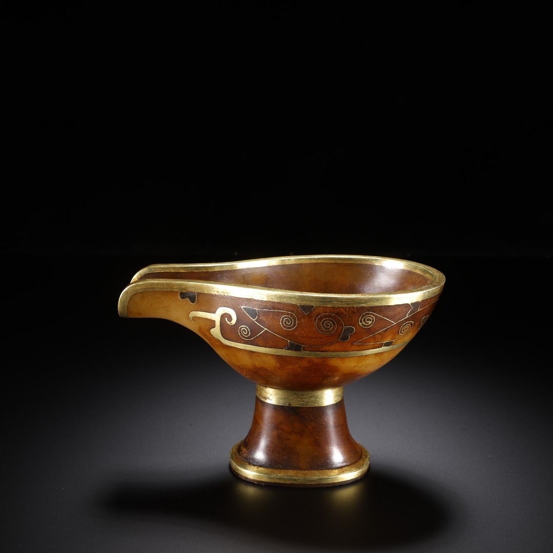 HAN HETIAN JADE INLAID GOLD HIGH FOOT : Long: 10.6cm(4.17in), Width: 6.5cm(2.56in), Height: 7.4cm(2.91in), Weight: 254g (0.560lb)Carved into archaic yi shape from aged jade covered with dense natural patina. Equipped with pouring spout and 