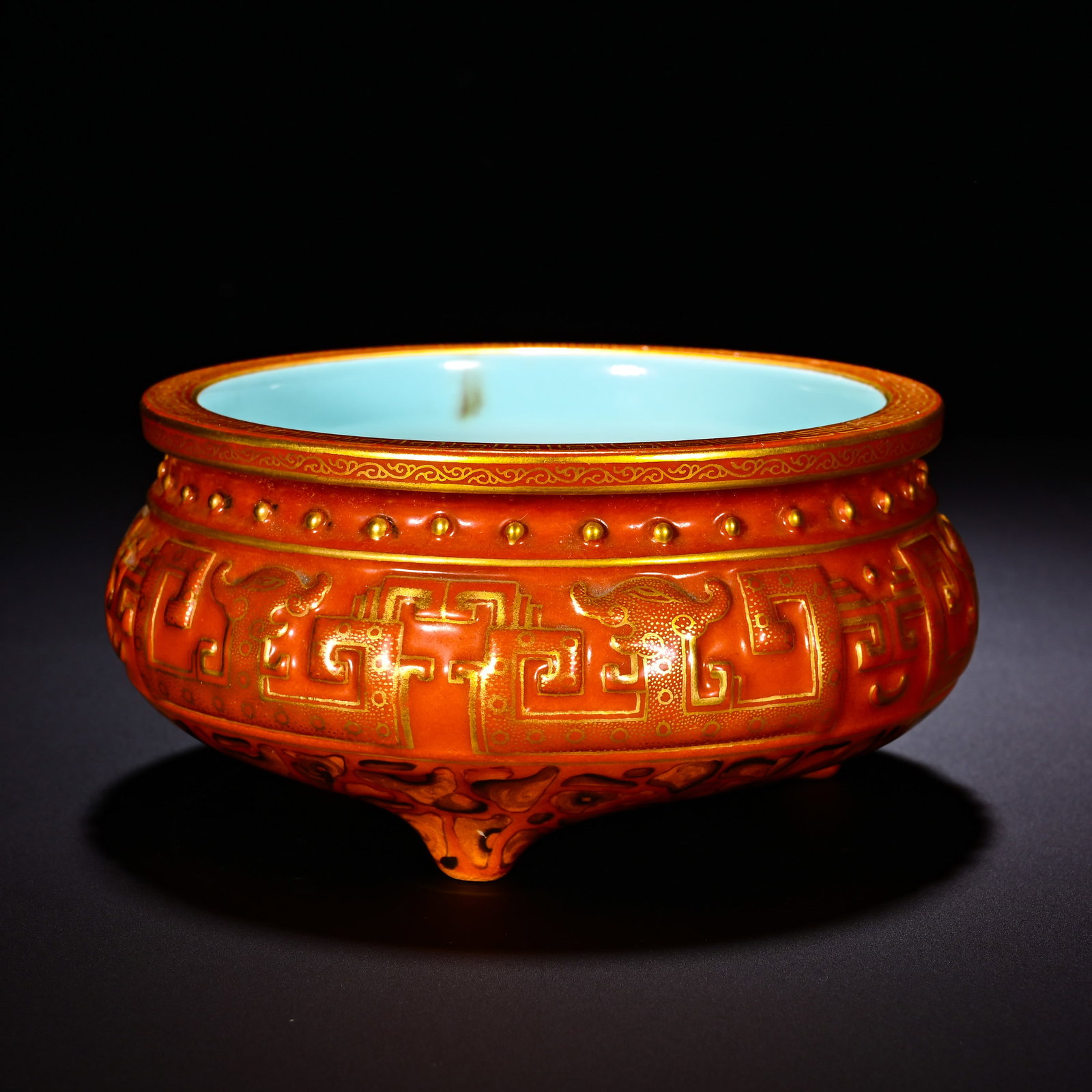 QING DYNASTY QIANLONG ALUM RED GROUND RELIEF GILDED ANTIQUE ???? PATTERN THREE-LEGGED STOVE: Height: 6.5cm(2.56in), Diameter: 13cm(5.12in)Tripod censer with flared rim and bulging belly, interior glazed in turquoise?green. Gilt?decorated rim, surmounted by a row of raised bosses below. The ex