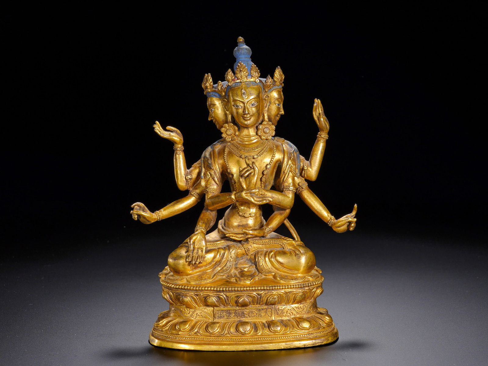 A GILDED BRONZE SEATED STATUE OF EMPEROR QIANLONG OF THE QING DYNASTY: Height: 18cm(7.09in), Width: 11.5cm(4.53in), Weight: 1550g (3.417lb)Iconographically authentic: three faces and eight arms. The central face bears a serene expression, flanked by two secondary faces. 