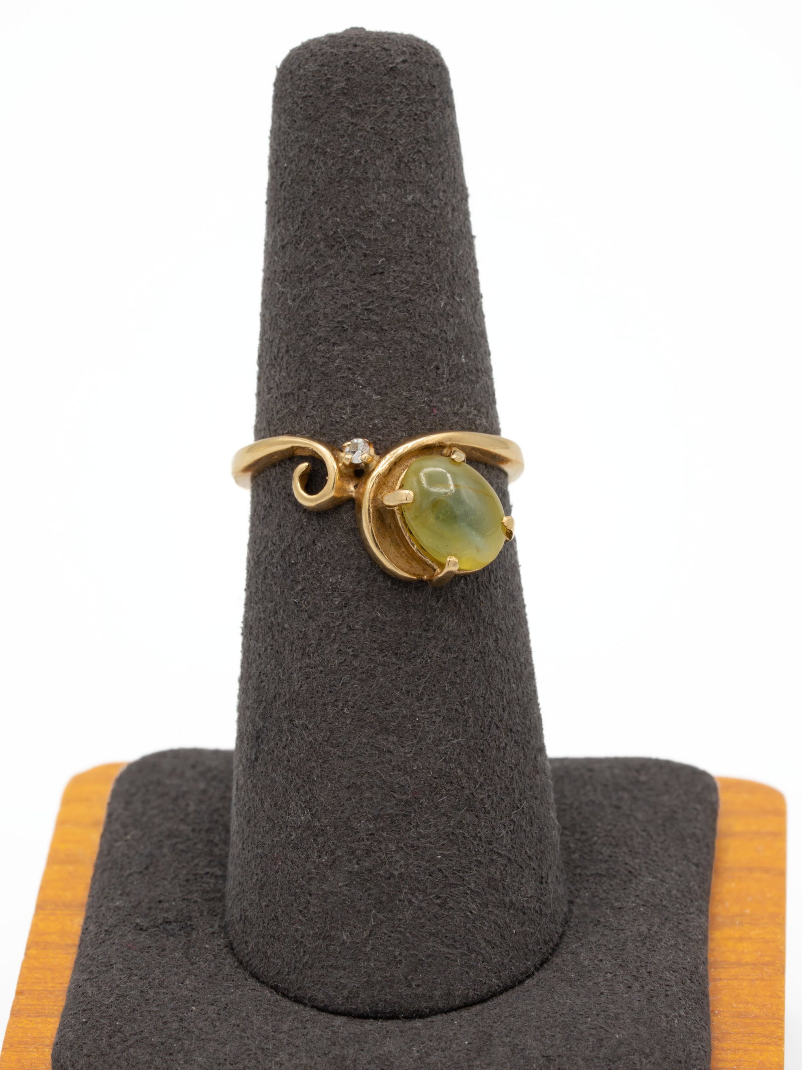 14K Chatoyant Cabochon Bypass Ring: Size 6 ring in stamped 14 karat yellow gold, gross weight 3.41 grams. Bypass / scroll mount set with a greenish-yellow oval cabochon approximately 6 × 8 mm (about 5 mm tall) showing chatoyancy (desk 